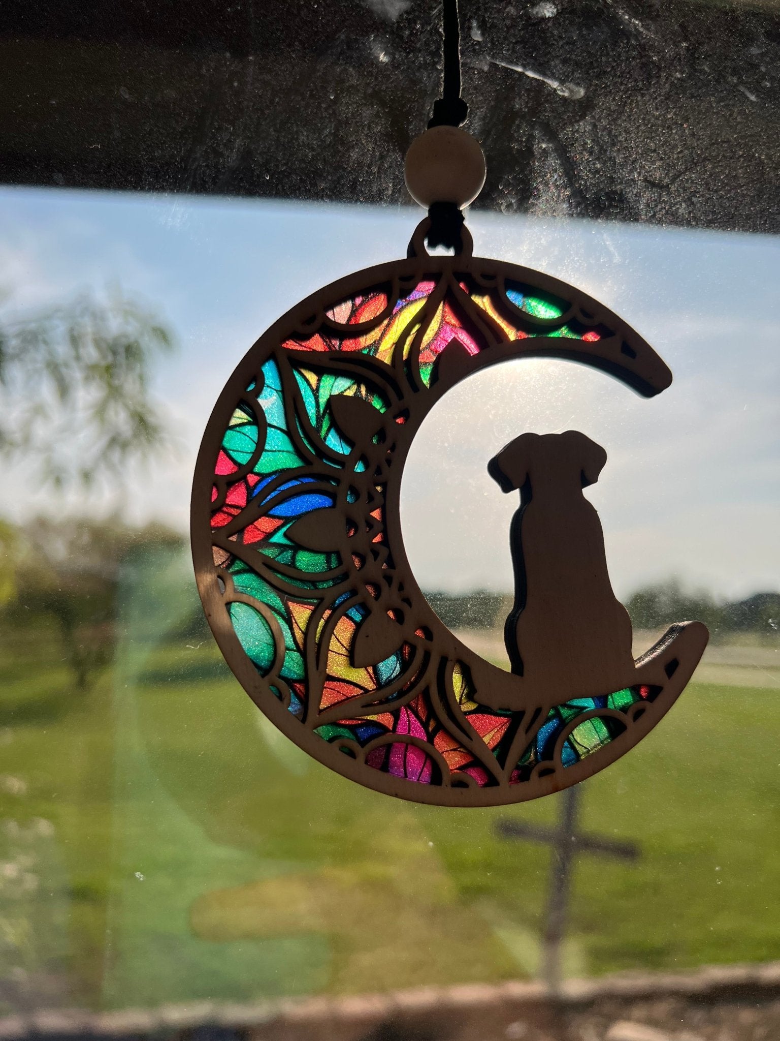 Wood and acrylic suncatcher with a dog on the moon design, featuring stained glass effect in sunlight.