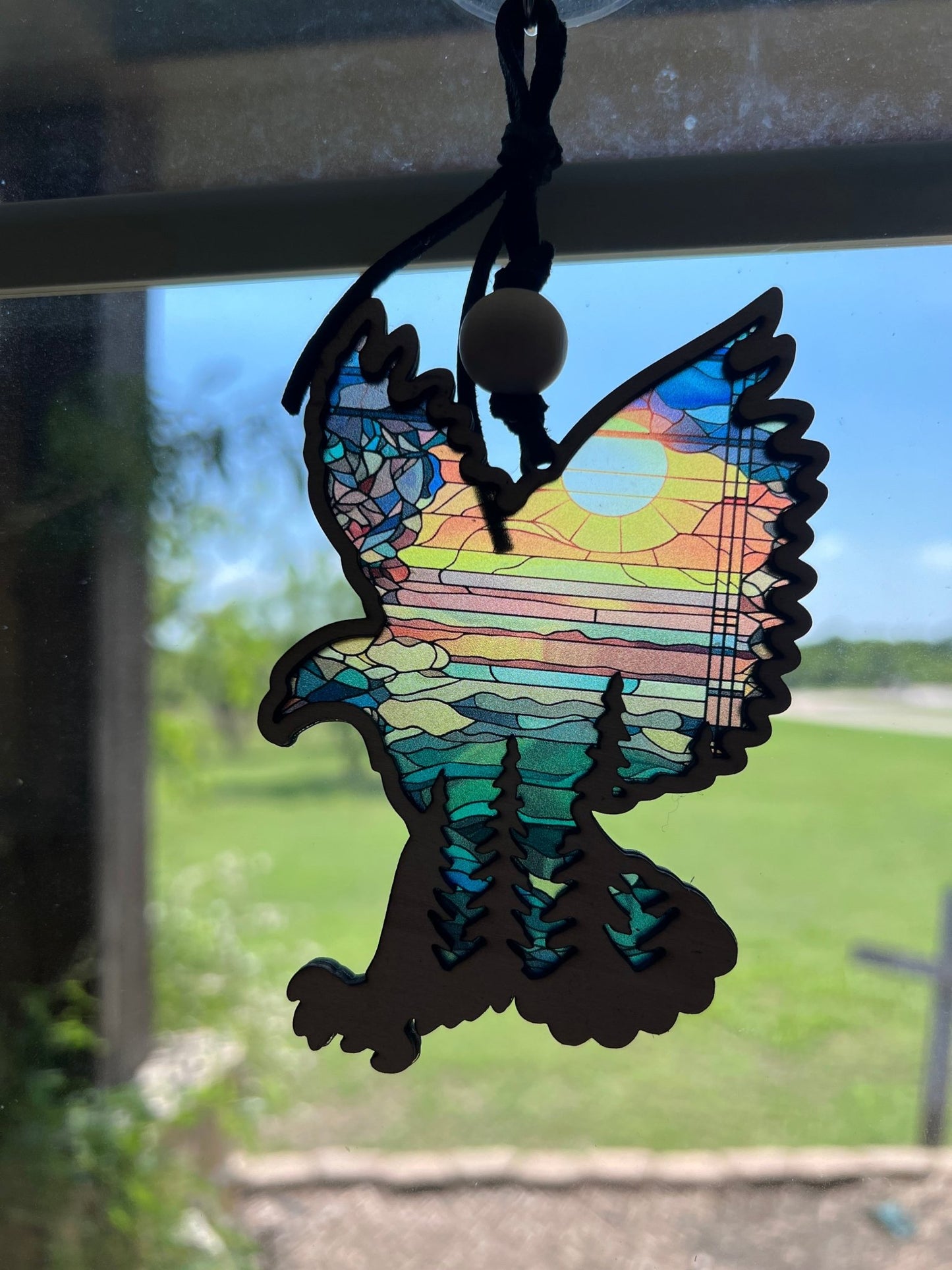 Eagle in flight over mountains suncatcher in wood and multicolor acrylic in sunlight.