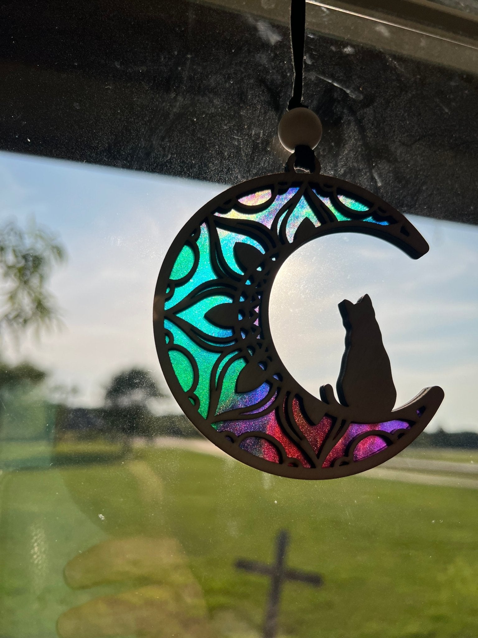 A charming Cat on the Moon Suncatcher made of natural wood and multicolor acrylic in sunlight.
