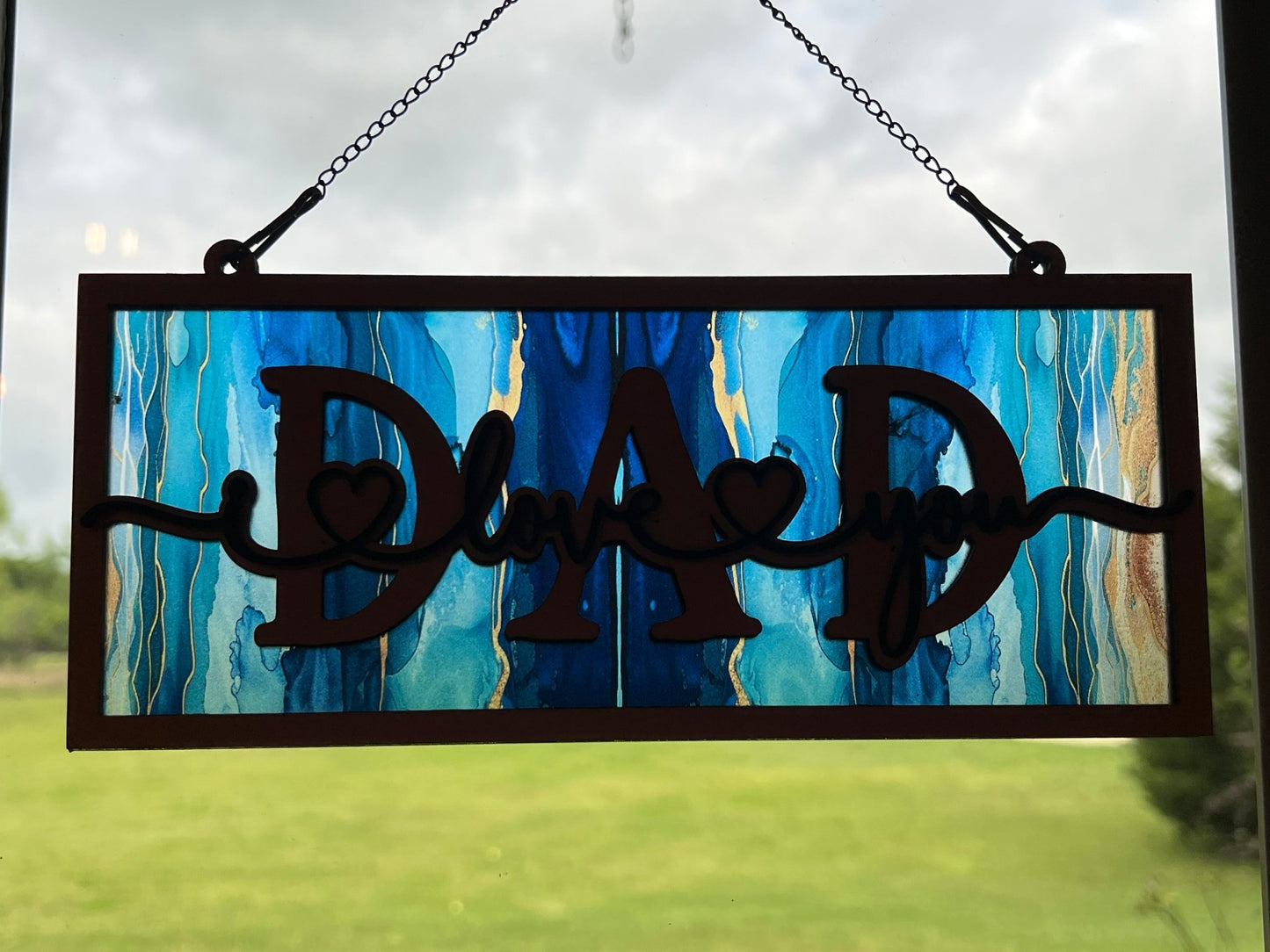 Handmade 'Dad I Love You' wood and acrylic suncatcher with stained glass effect. in sunlight