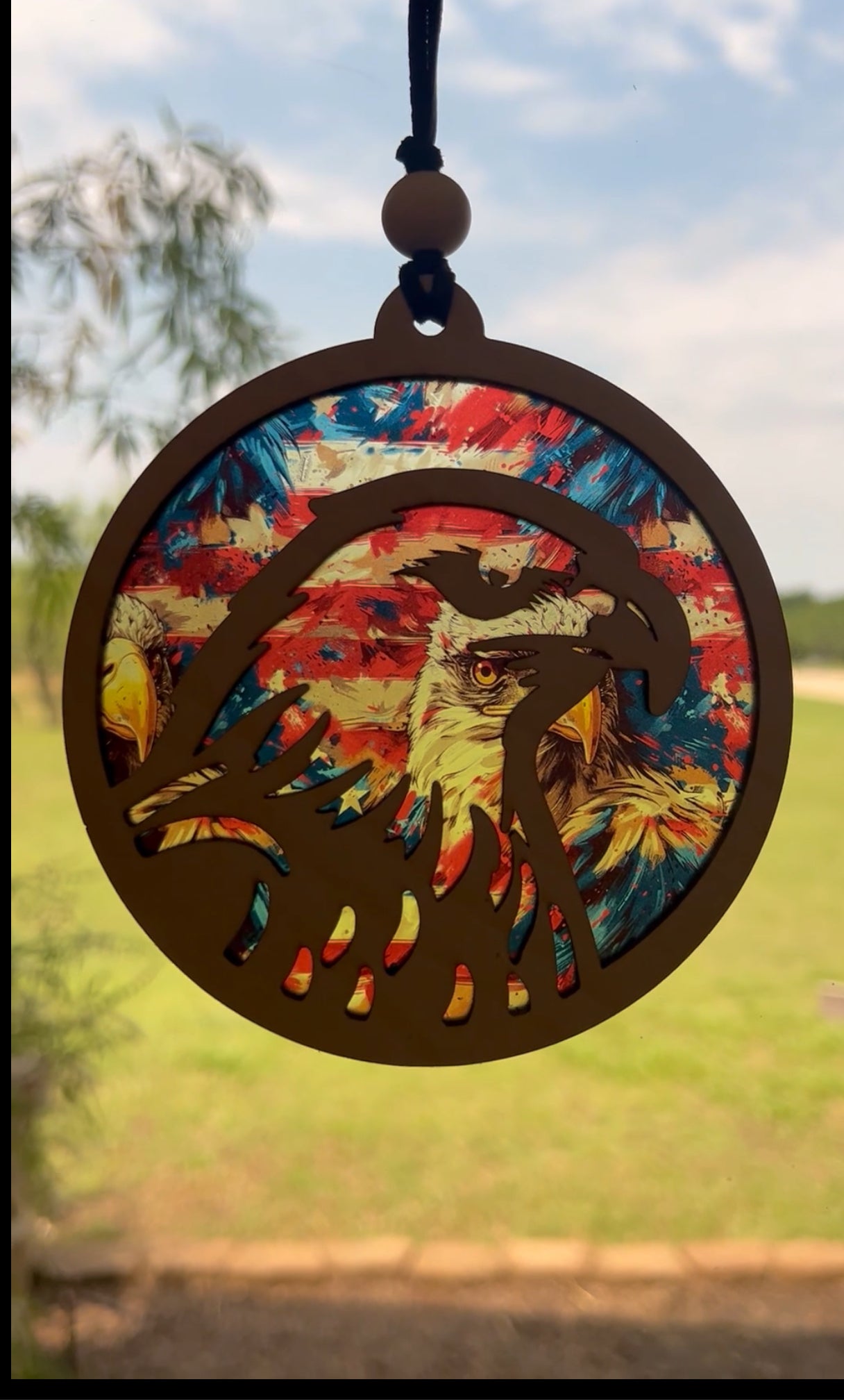Eagle-shaped suncatcher with natural wood and multicolor acrylic, capturing light beautifully lighted.