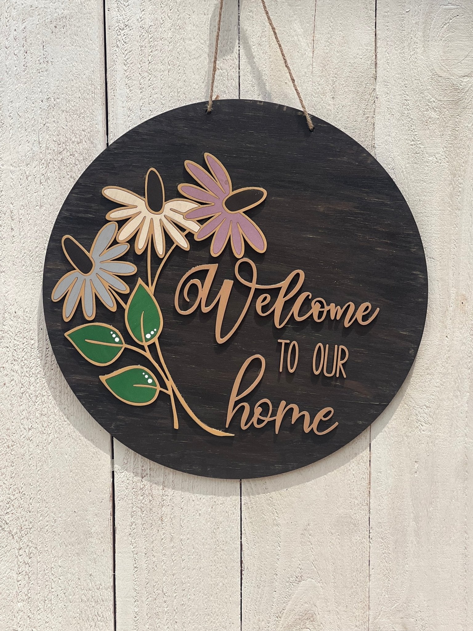 Rustic coneflower welcome door hanger made from walnut-stained wood with multicolor accents, on white fence.