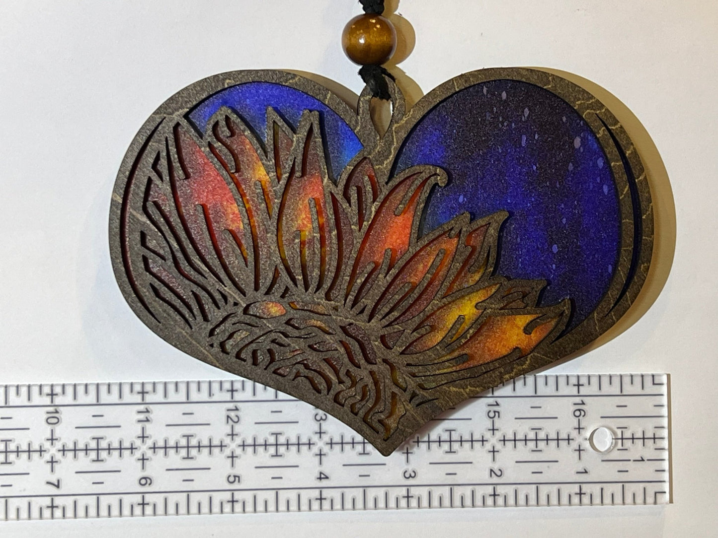 Heart-shaped suncatcher with sunflower design made of wood and multicolor acrylic, creating a stained glass effect unlit.