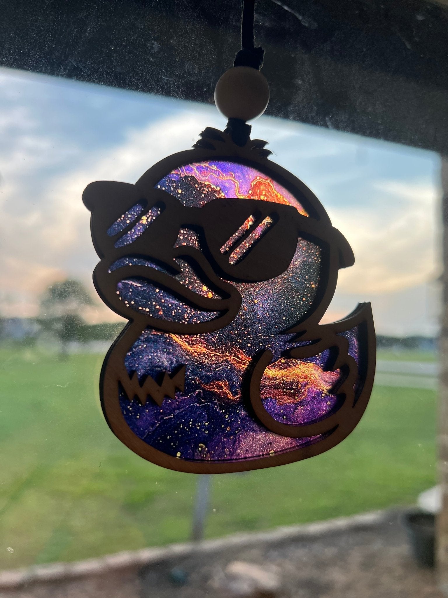 Colorful rubber duck suncatcher in wood and acrylic, rustic-modern decor in sunlight.