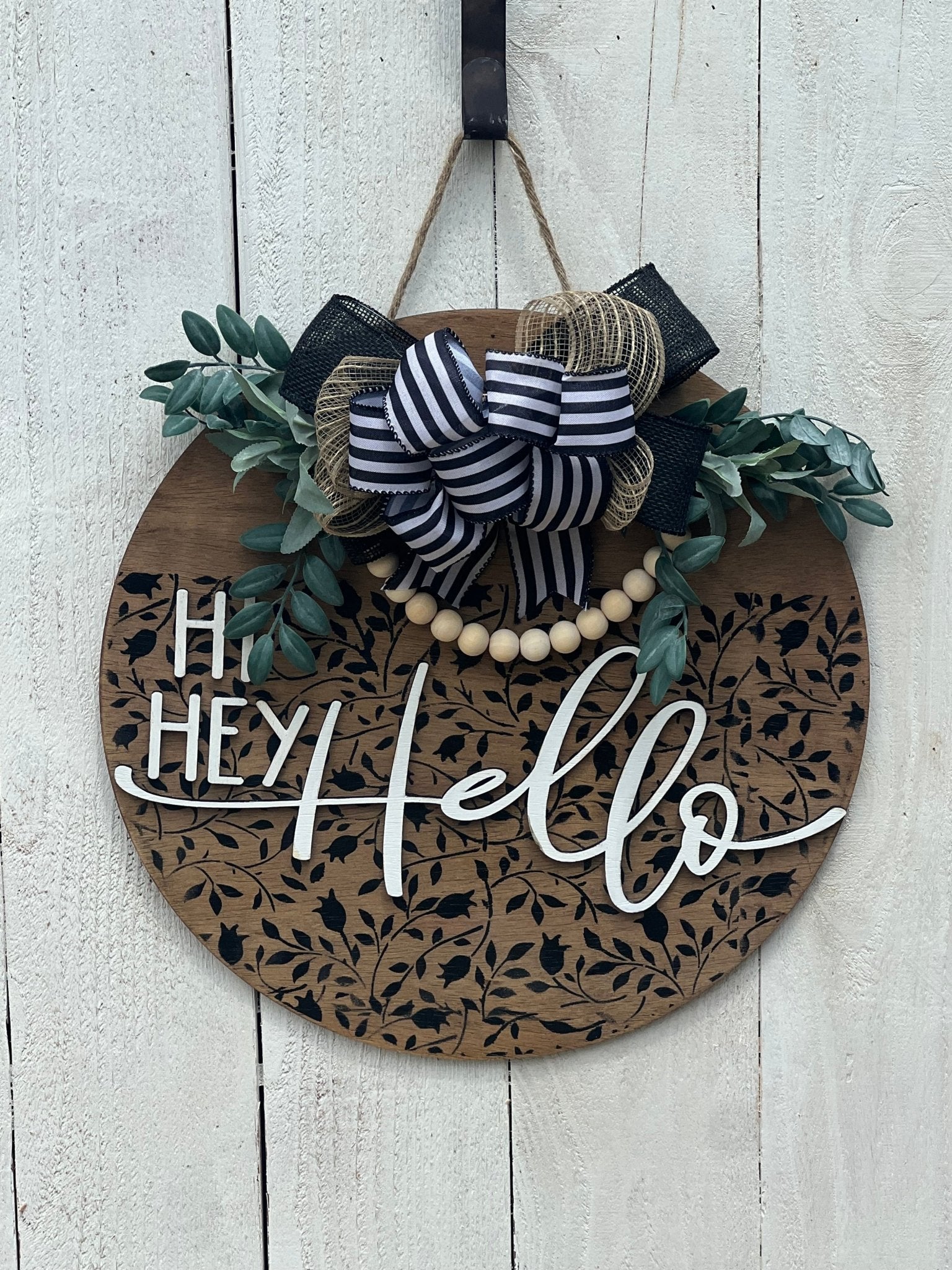 Round wood black Mini Flower and Vine door sign with natural wood accents hanging on a white fence.