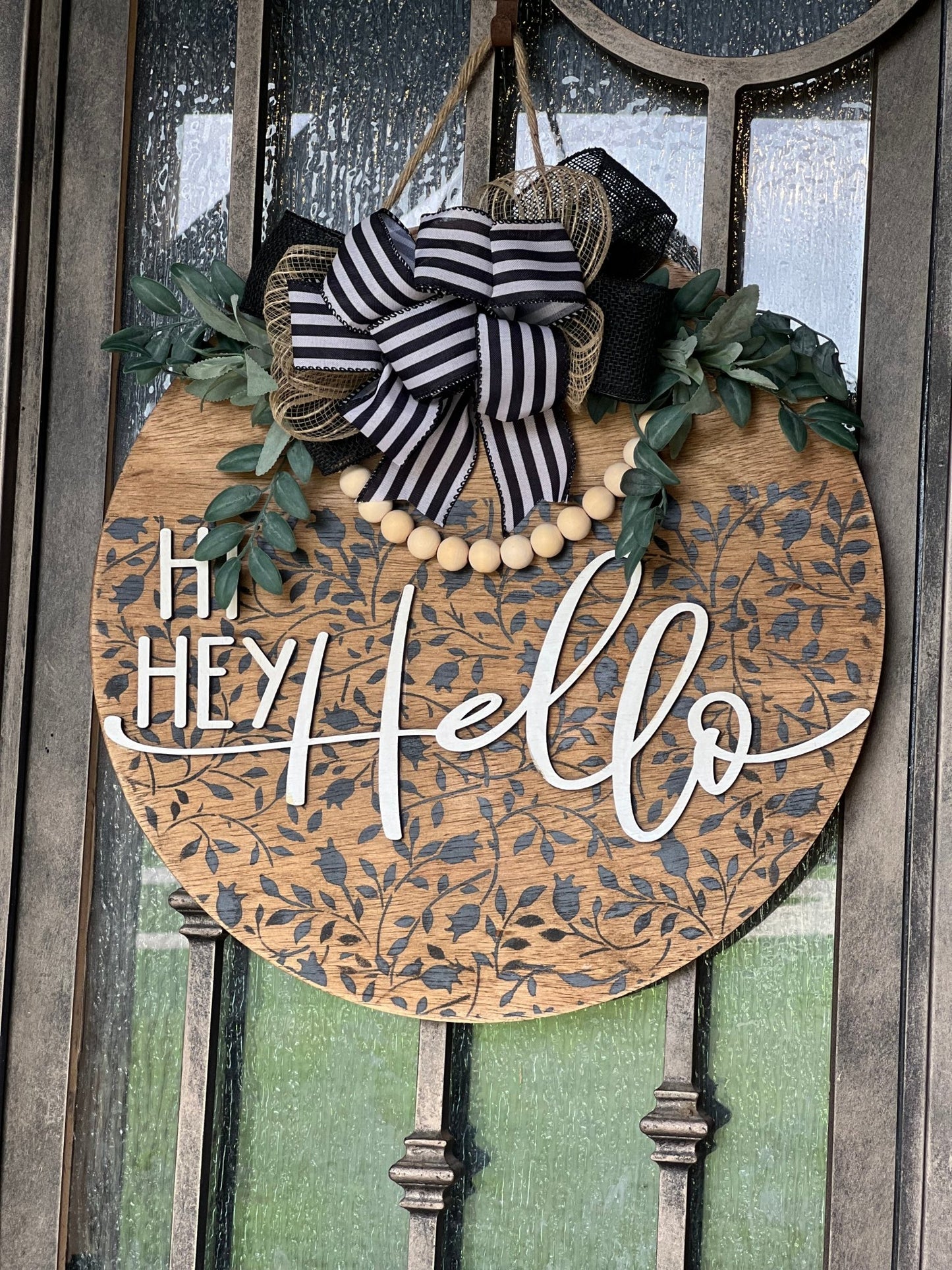 Round wood black Mini Flower and Vine door sign with natural wood accents hanging on a metal door.