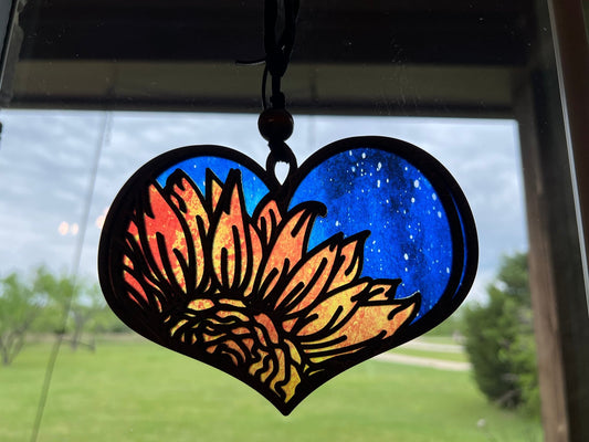 Heart-shaped suncatcher with sunflower design made of wood and multicolor acrylic, creating a stained glass effect in sunlight.