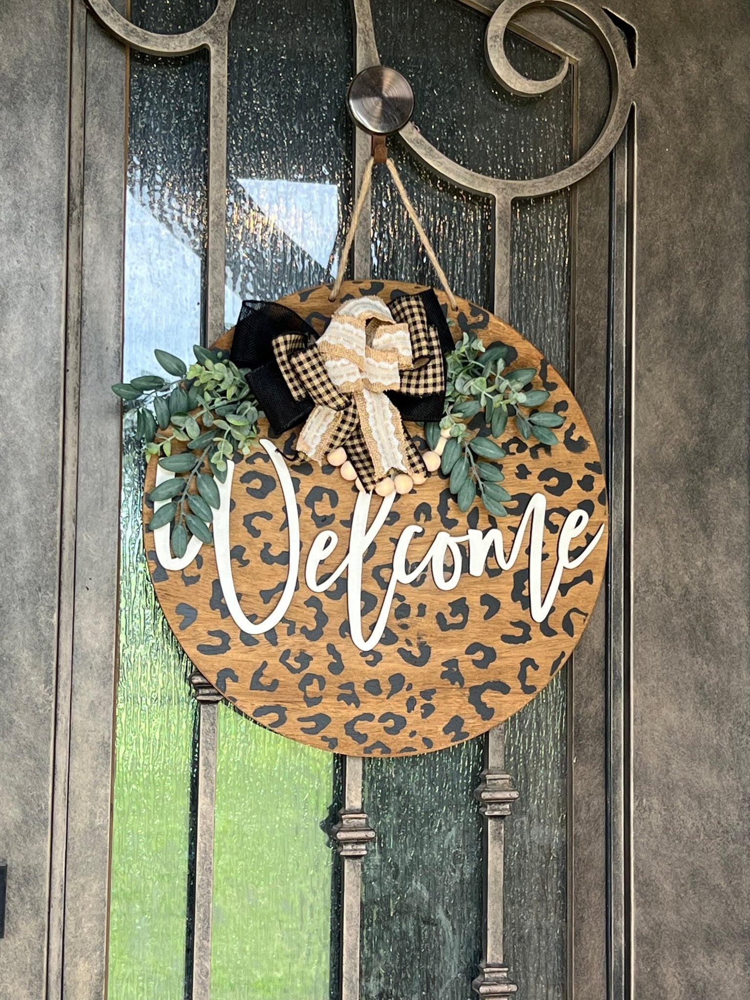 A rustic wooden door hanger with leopard print design, perfect for chic decor hanging on a metal door.