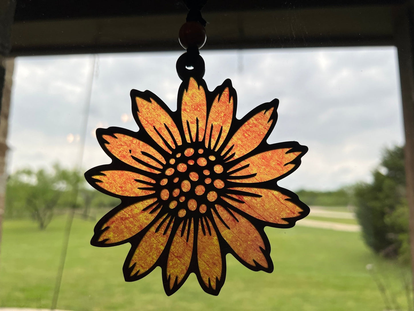 Sunflower stained glass effect suncatcher made of natural wood and acrylic in sunlight.