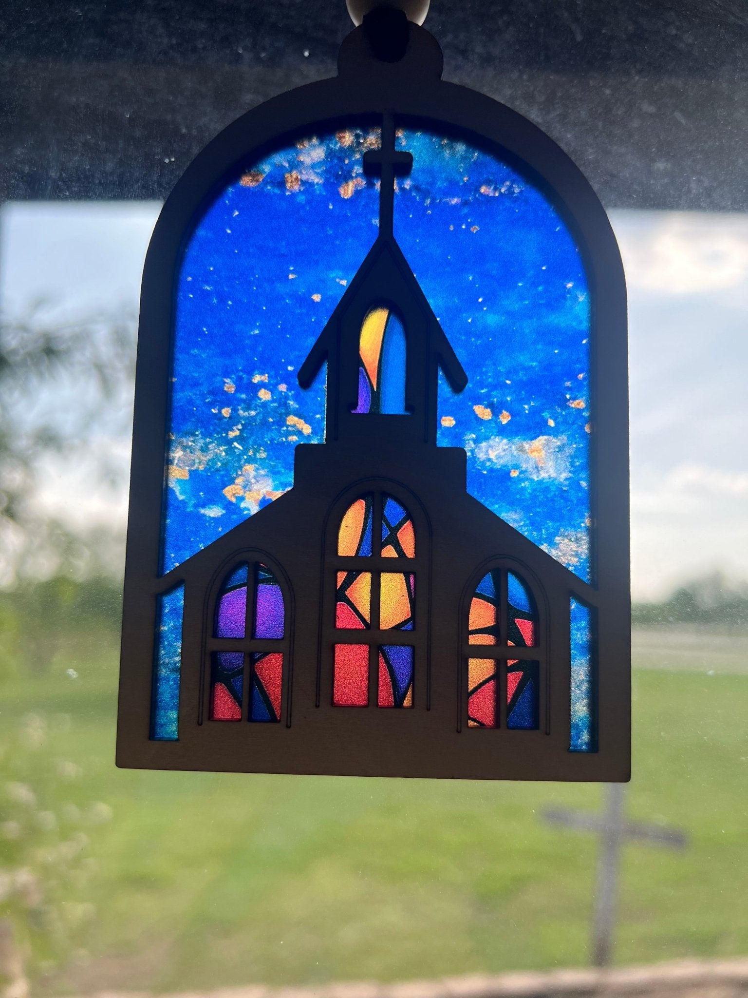 Colorful church suncatcher with stained glass effect, crafted from wood and acrylic in sunlight.