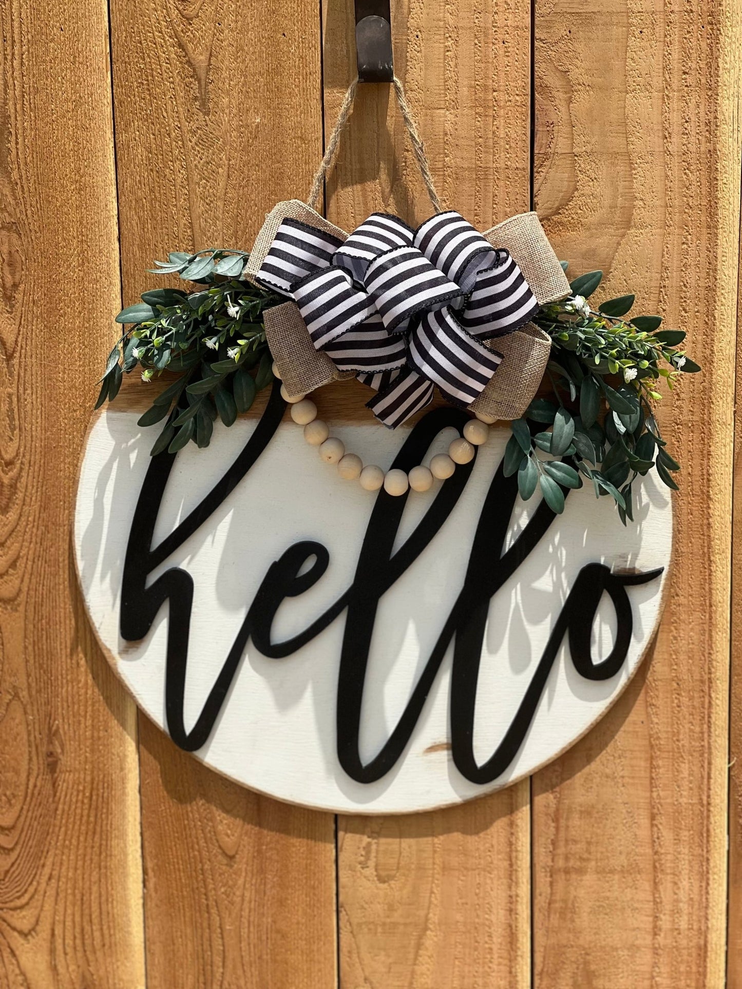 White Hello Door Hanger in rustic wood with black text, 18 inche on unpainted fences.