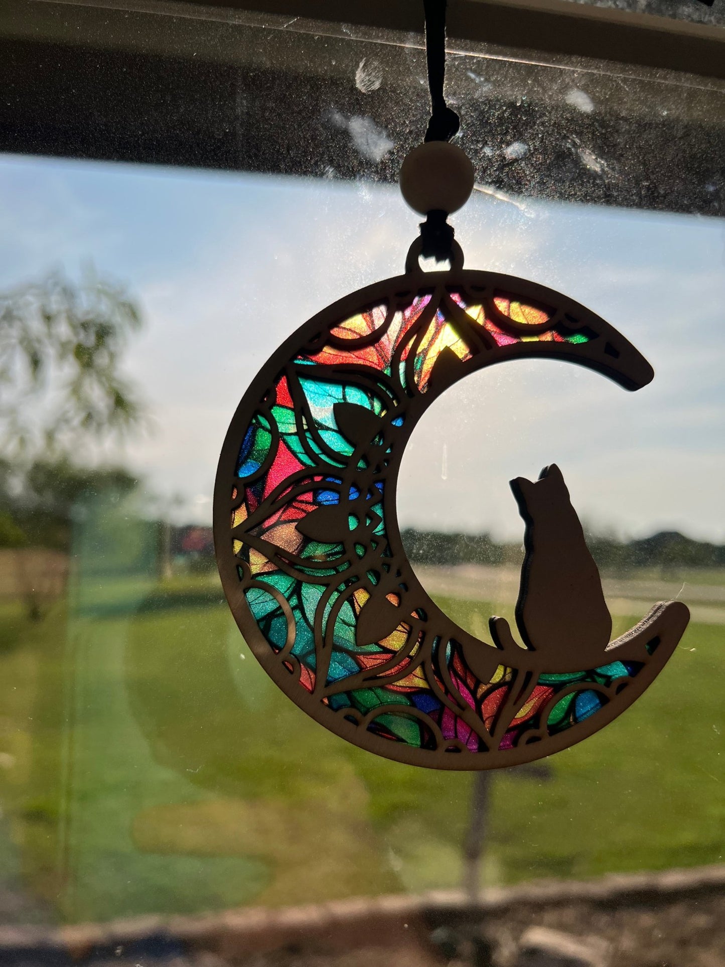 Rustic Cat on the Moon suncatcher with wood and acrylic, in natural hues in sunlight.