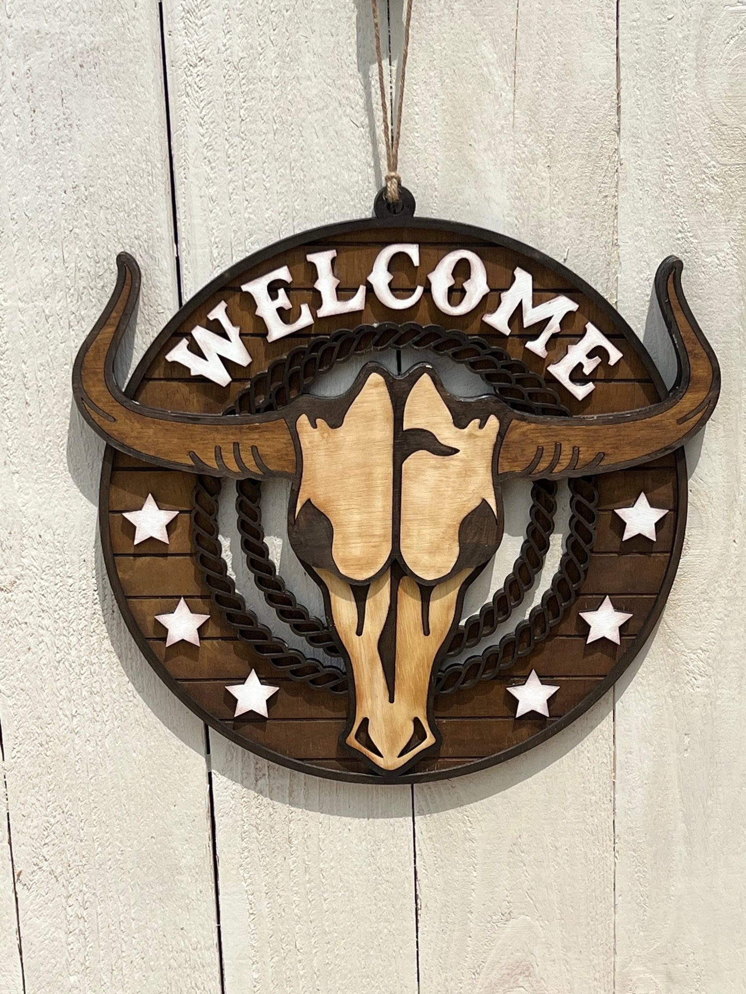 Rustic Longhorn Wood Door Hanger with natural wood texture and warm walnut stain on white fence.