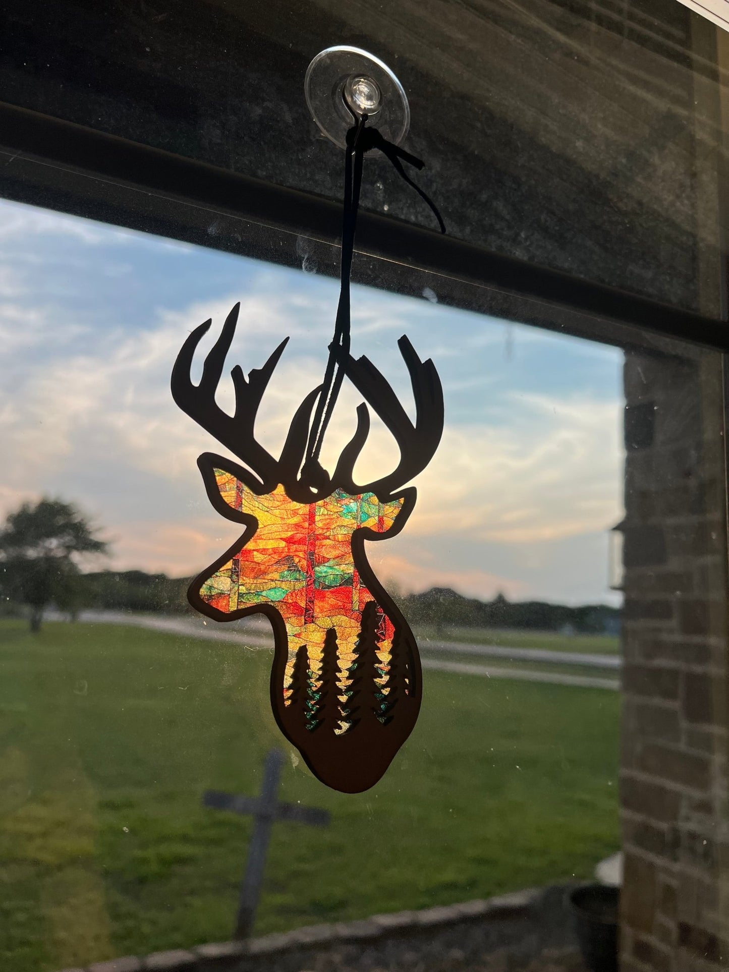 Rustic buck motif suncatcher made of wood and acrylic, multicolor, 6.25x4 inches in sunlight.