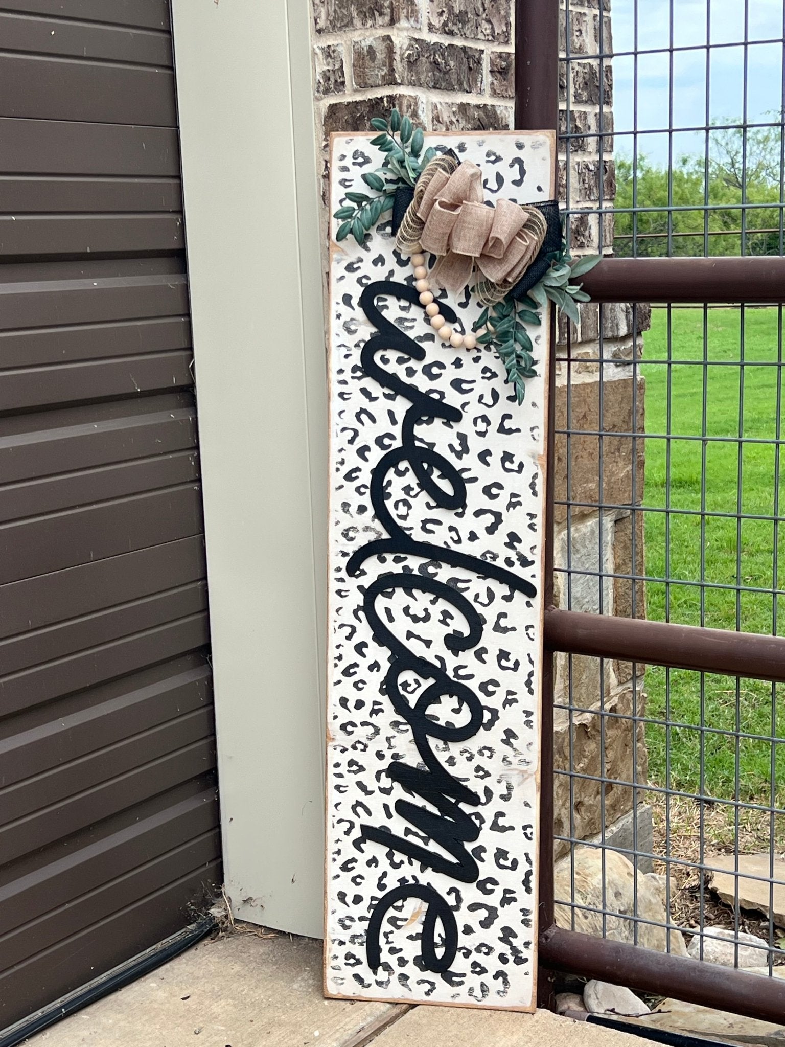 White leopard print wooden door lean, rustic style, perfect for entryway decor leasning beside garage door and fence..