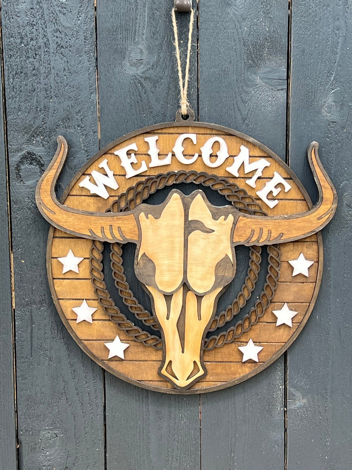 Rustic Longhorn Wood Door Hanger with natural wood texture and warm walnut stain on black fence.