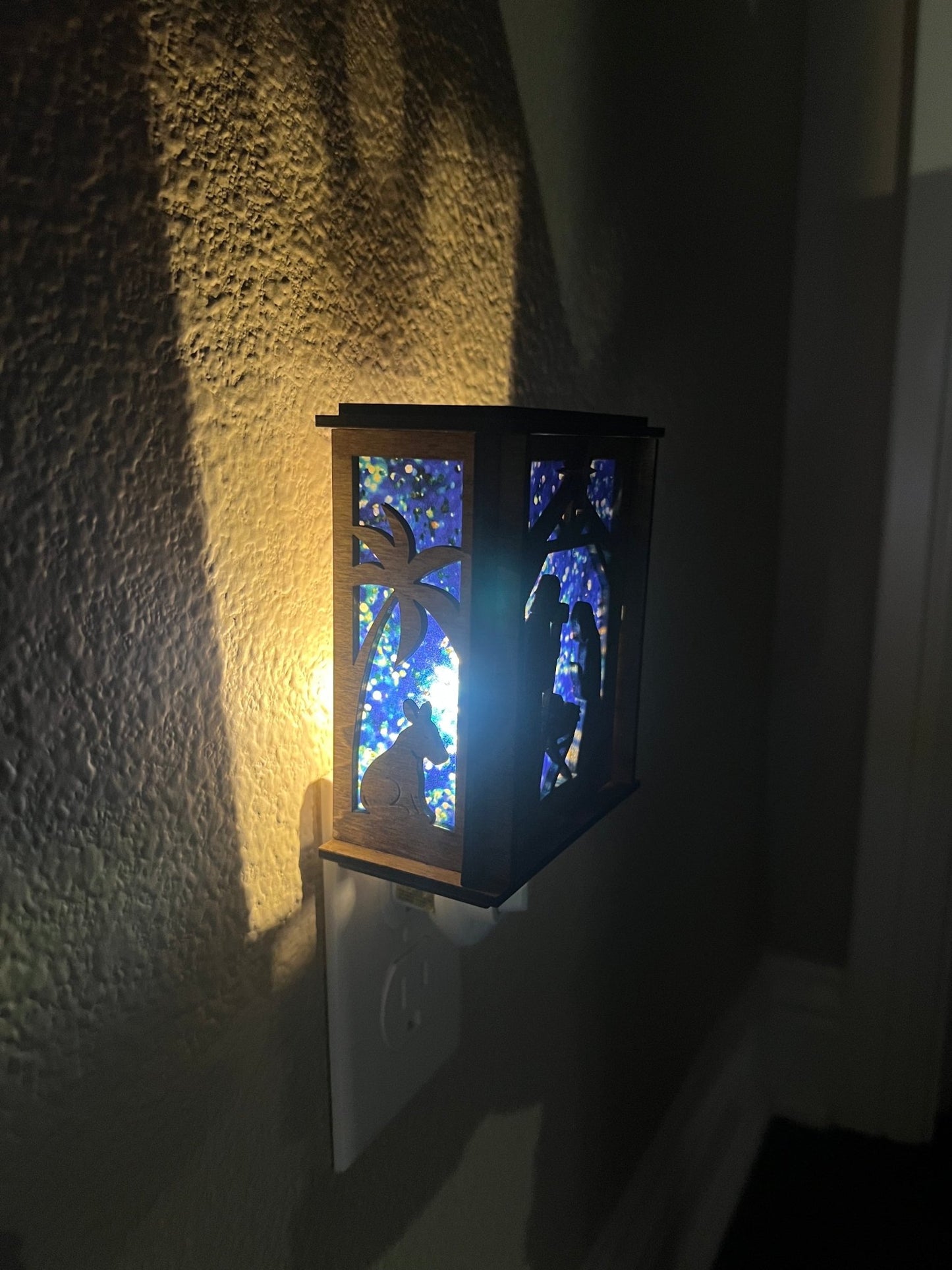 A Christmas Nativity Lantern Nightlight in golden oak with wood and acrylic materials - lit with right side view.