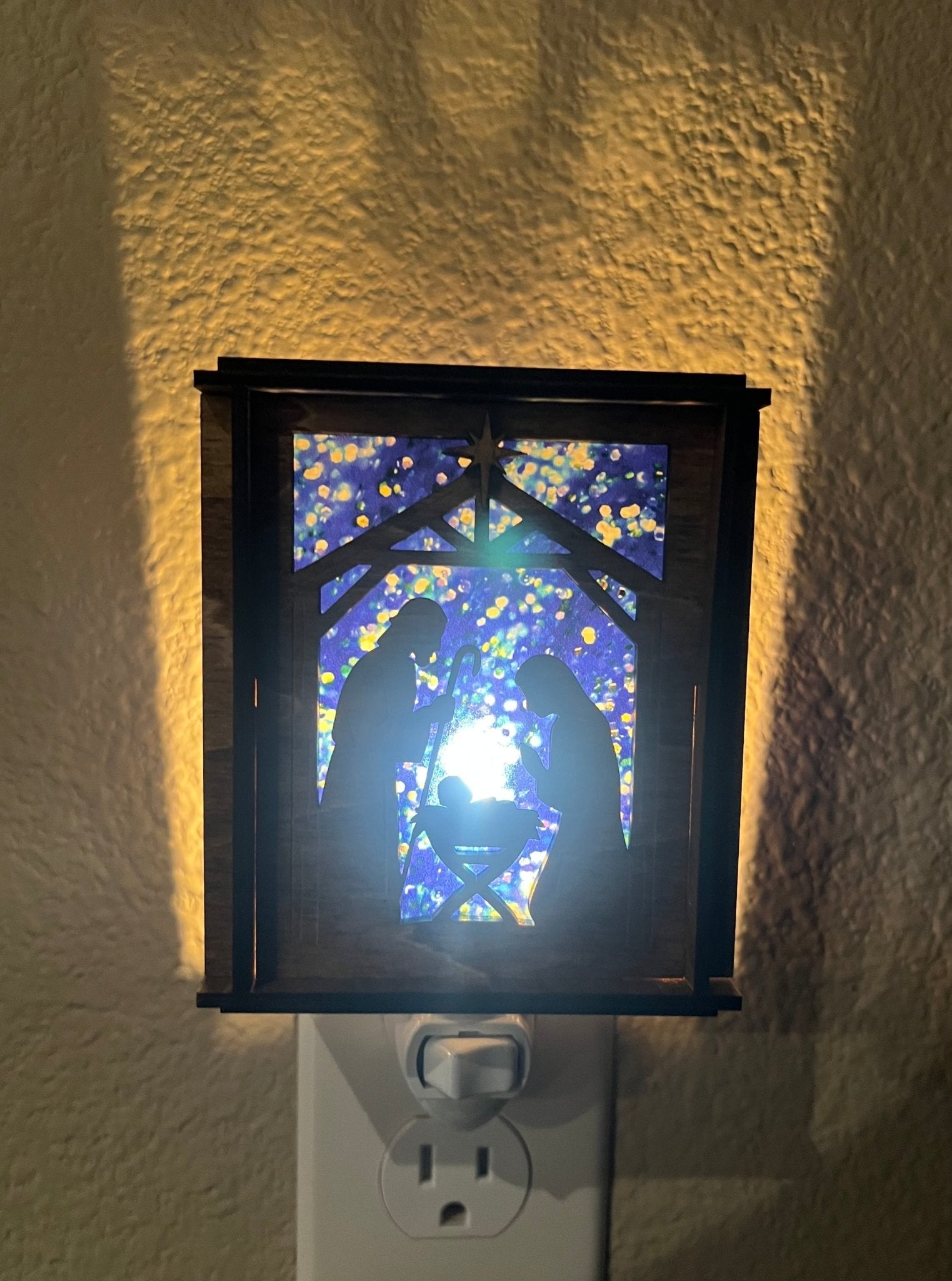 A Christmas Nativity Lantern Nightlight in golden oak with wood and acrylic materials - lit with front view.