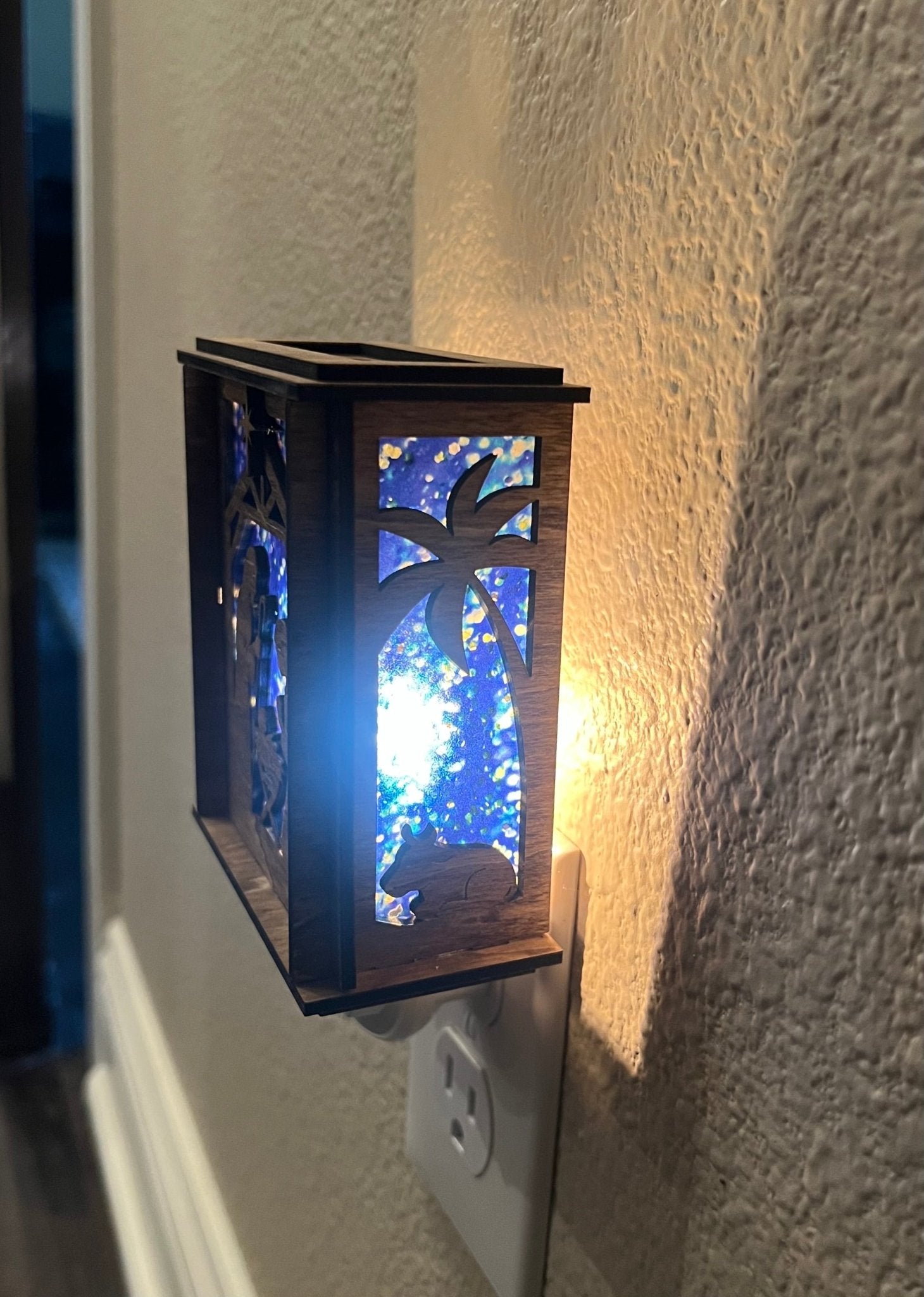 A Christmas Nativity Lantern Nightlight in golden oak with wood and acrylic materials  - lit right side with lights on.