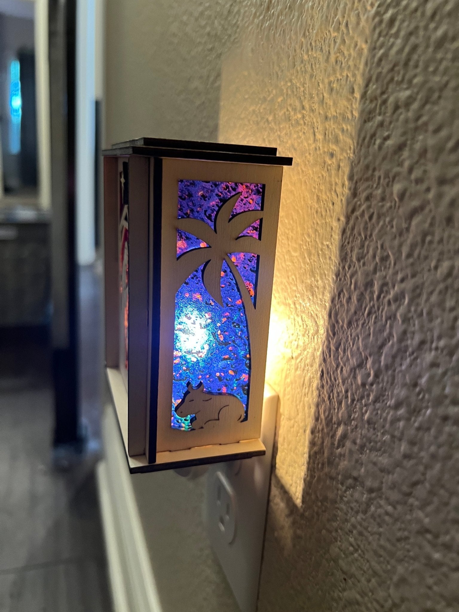 Natural wood Christmas Nativity Lantern Nightlight with multicolor designs lit with left side view.