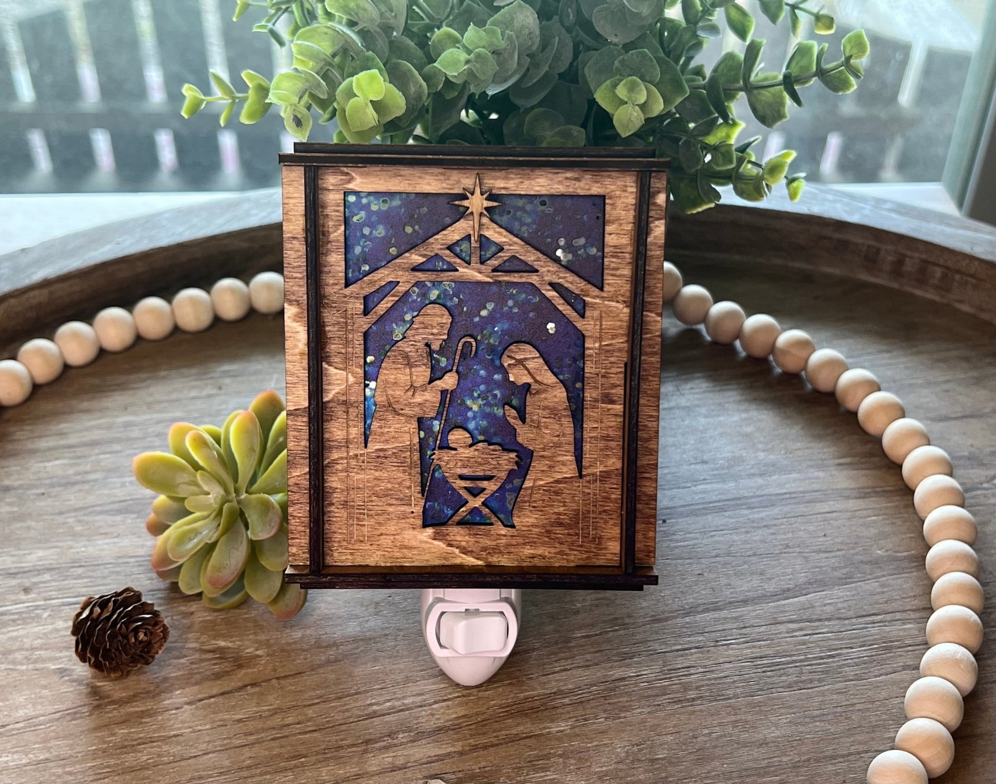 A Christmas Nativity Lantern Nightlight in golden oak with wood and acrylic materials i natural light.