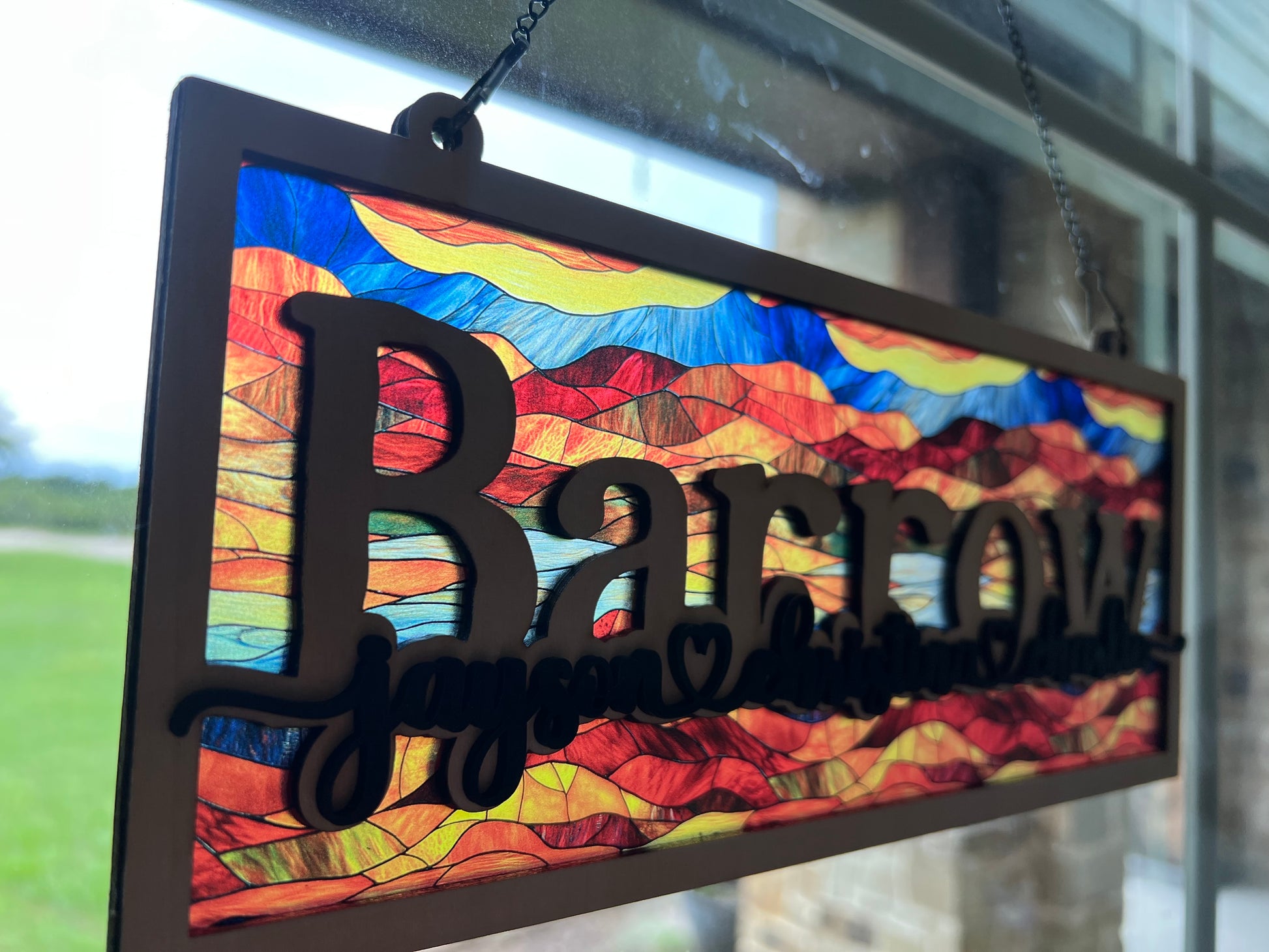 Family Personalized Suncatcher in natural wood and multicolor acrylic, showcasing rustic-modern style in sunlight from side.