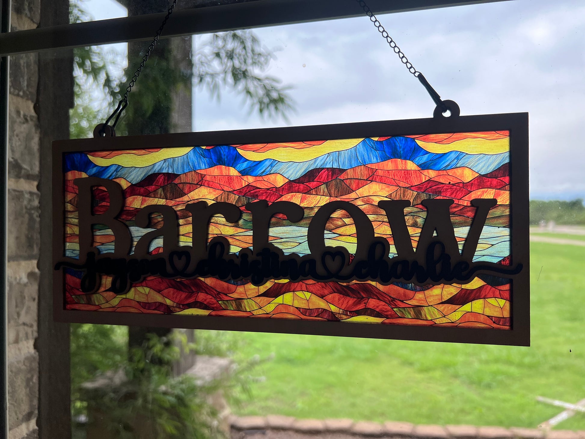 Family Personalized Suncatcher in natural wood and multicolor acrylic, showcasing rustic-modern style in sunlight from angle.