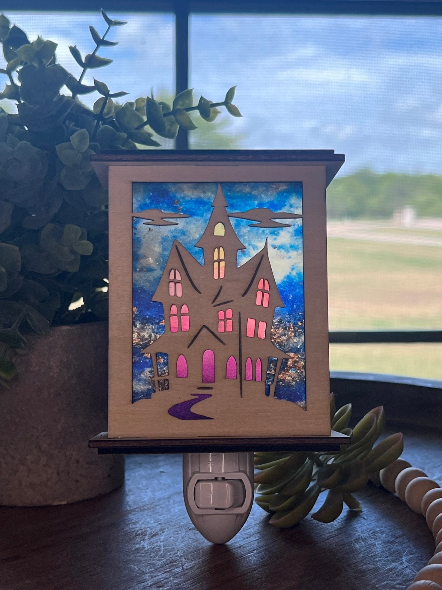 Halloween Haunted House Lantern Nightlight made from wood and acrylic, showcasing rustic charm and multicolor glow in sunlight.