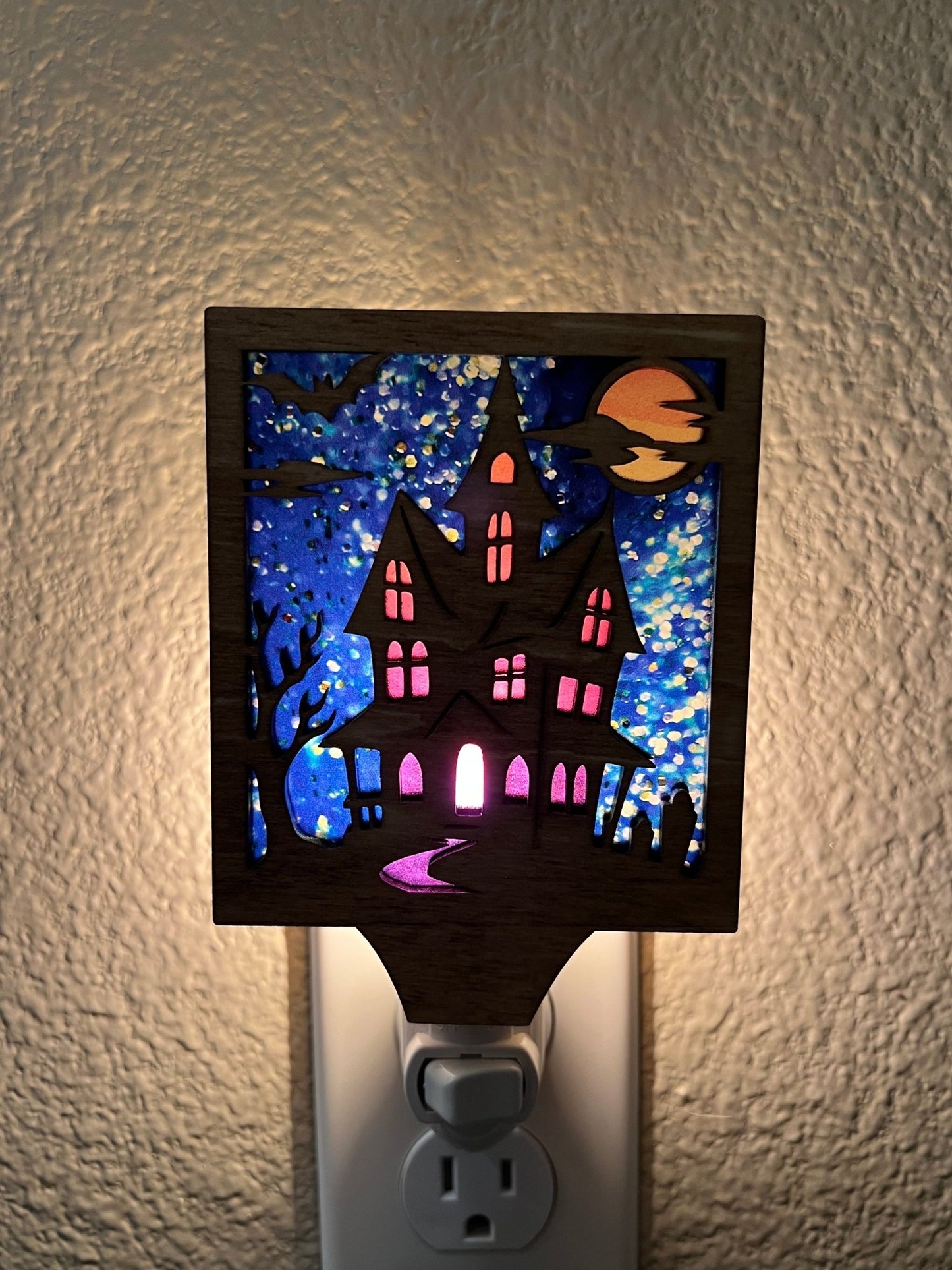Haunted House Nightlight made of wood and acrylic, golden oak stained, rustic decor, front view and plugged in.