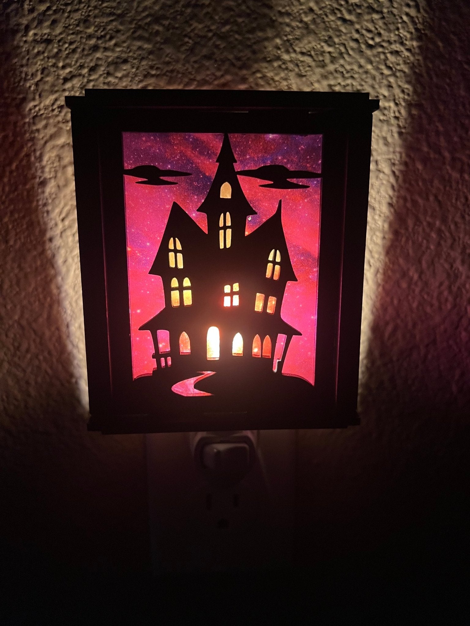 Black wooden haunted house nightlight with multicolor acrylic accents - front lit view.
