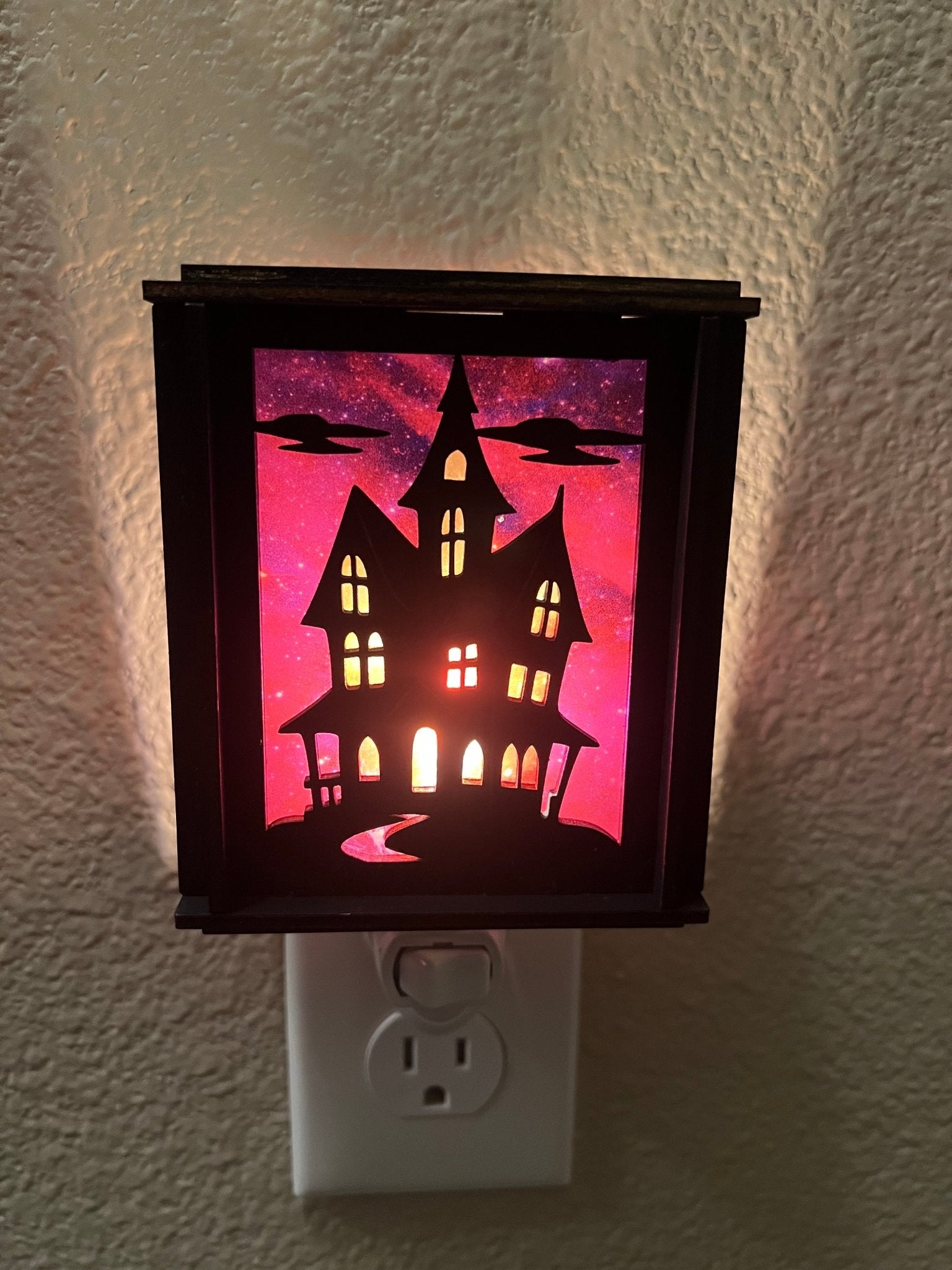 Black wooden haunted house nightlight with multicolor acrylic accents.
