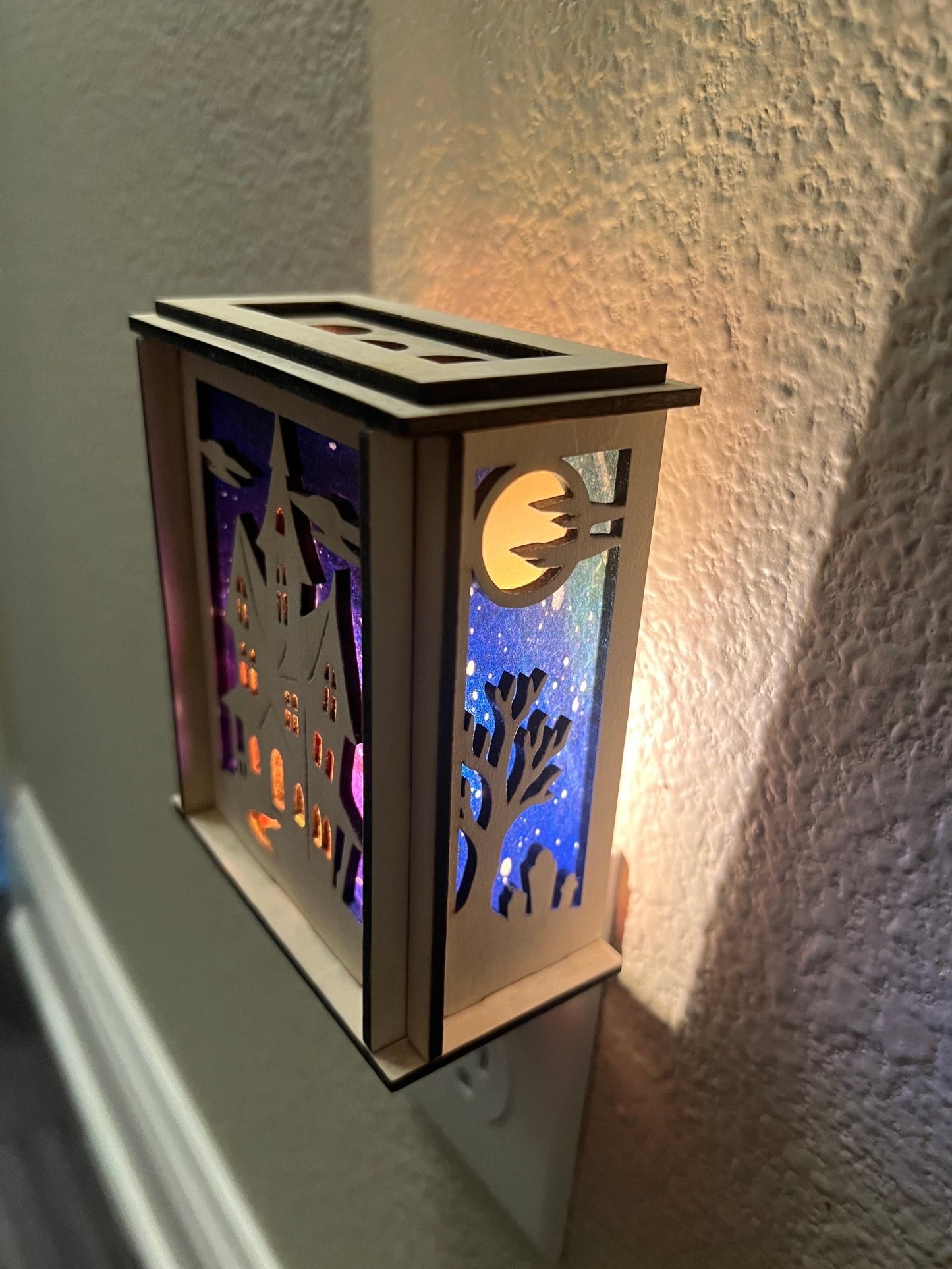 A haunted house-themed suncatcher with stained glass effect in black and multicolor acrylic - lighted from right side.