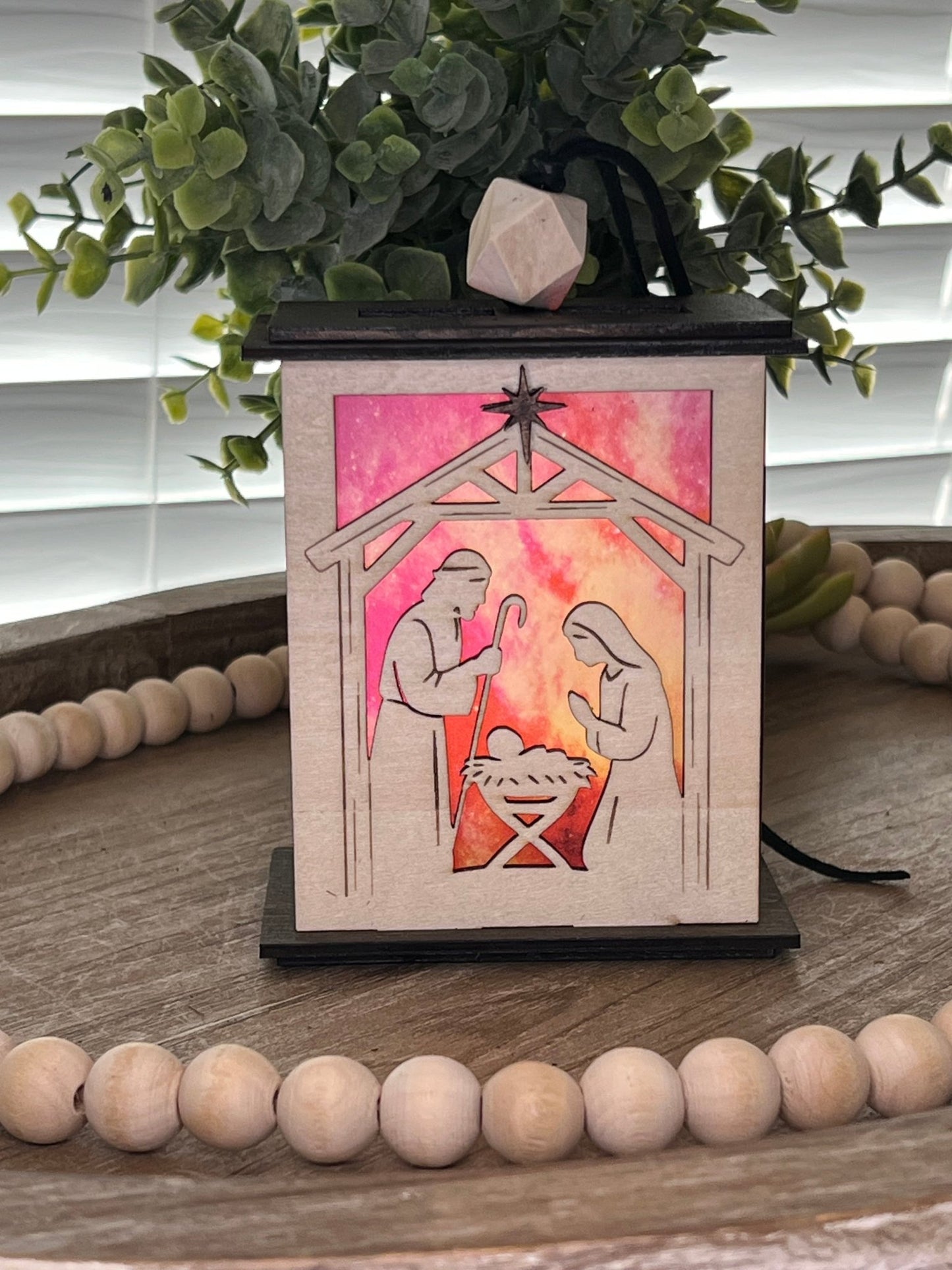 Lighted Christmas Nativity Lantern Ornament made with a natural and walnut stain and acrylic, front, lighted view.