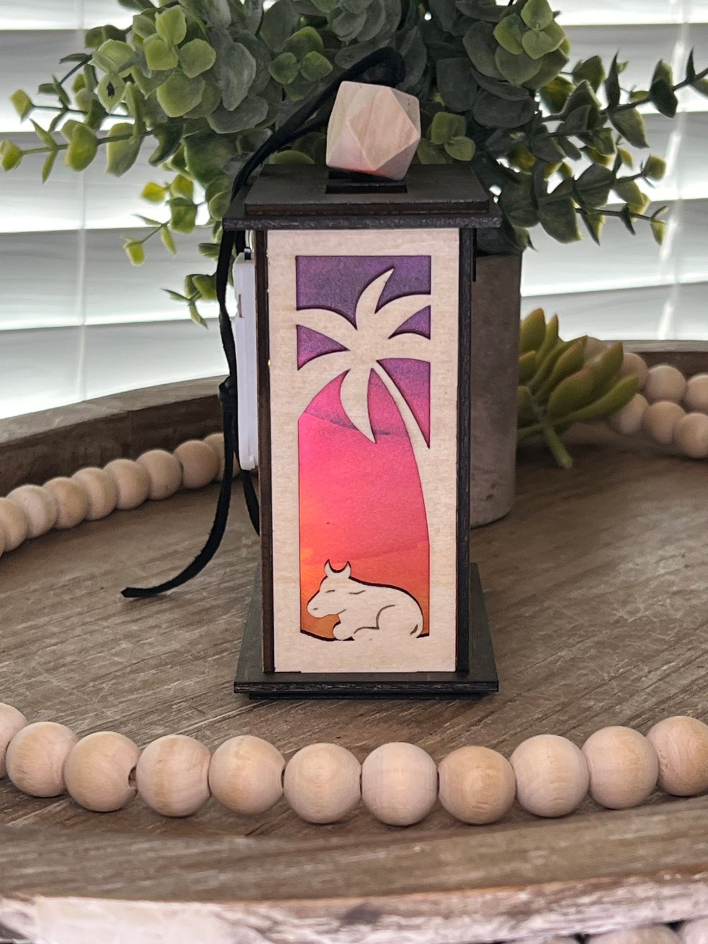 Lighted Christmas Nativity Lantern Ornament made with a natural and walnut stain and acrylic, left side, lighted view.