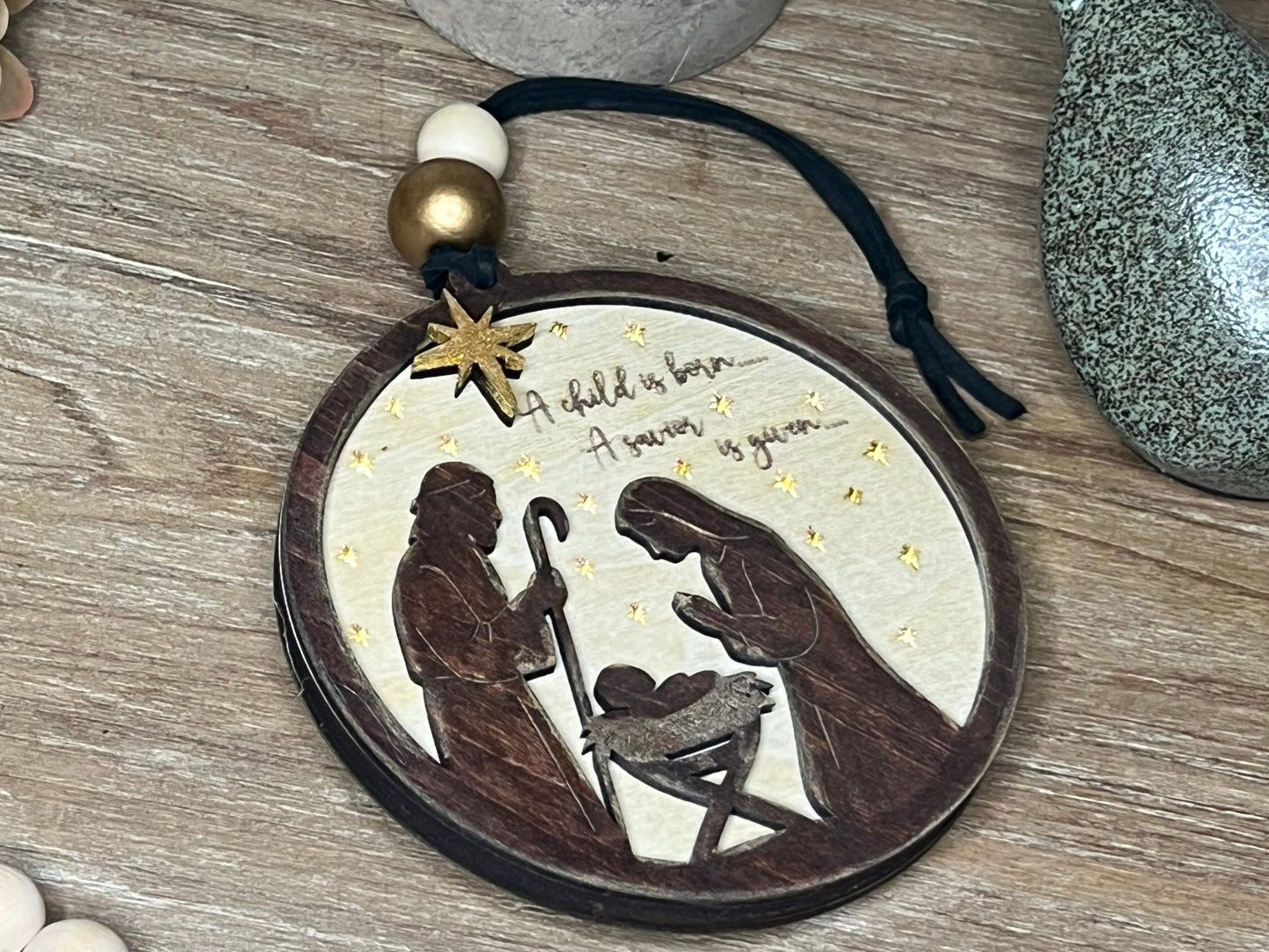 Lighted Christmas Nativity Ornament in natural wood with walnut stain lying on a tray.