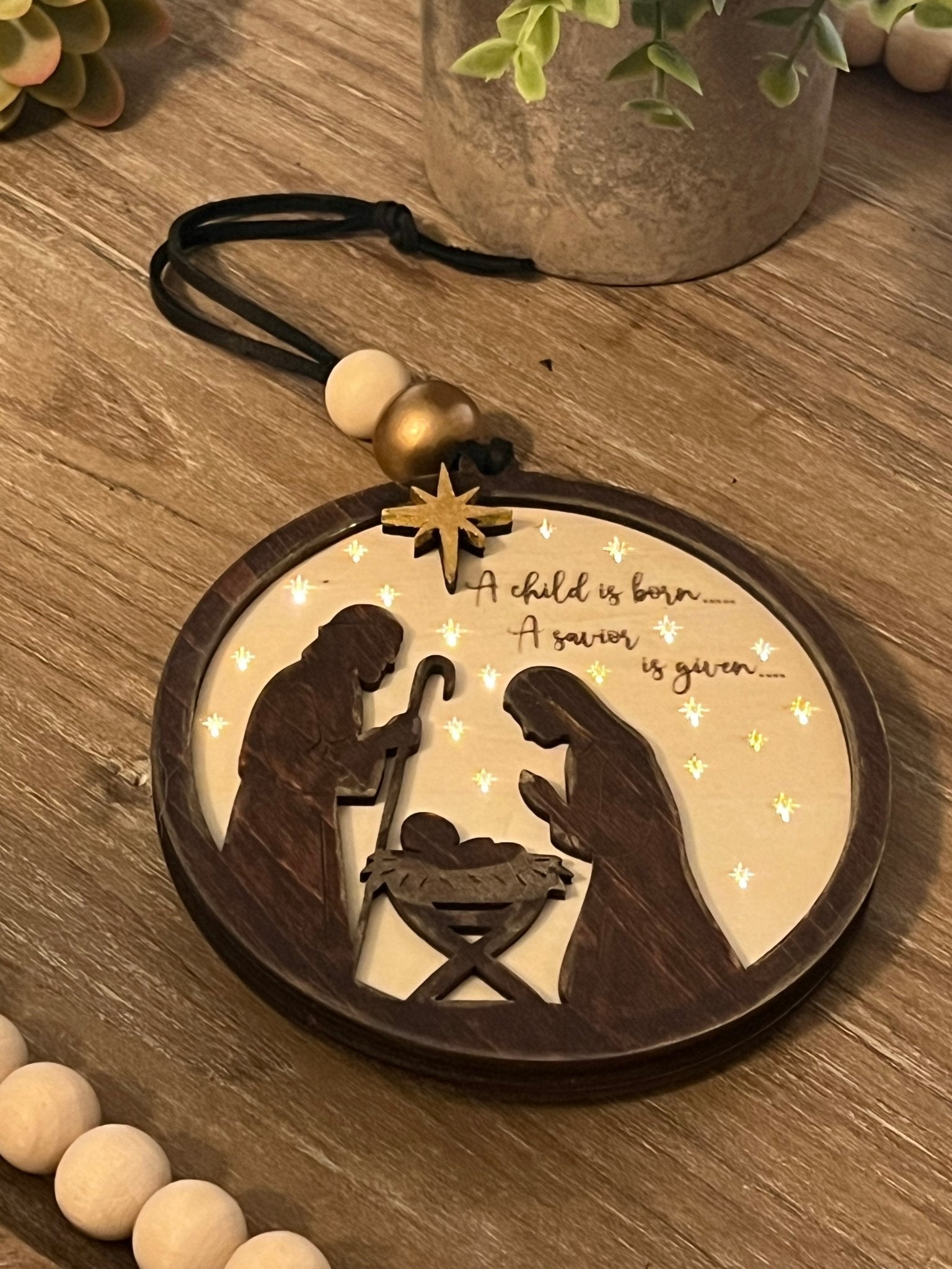 Lighted Christmas Nativity Ornament in natural wood with walnut stain lit and lying on tray.