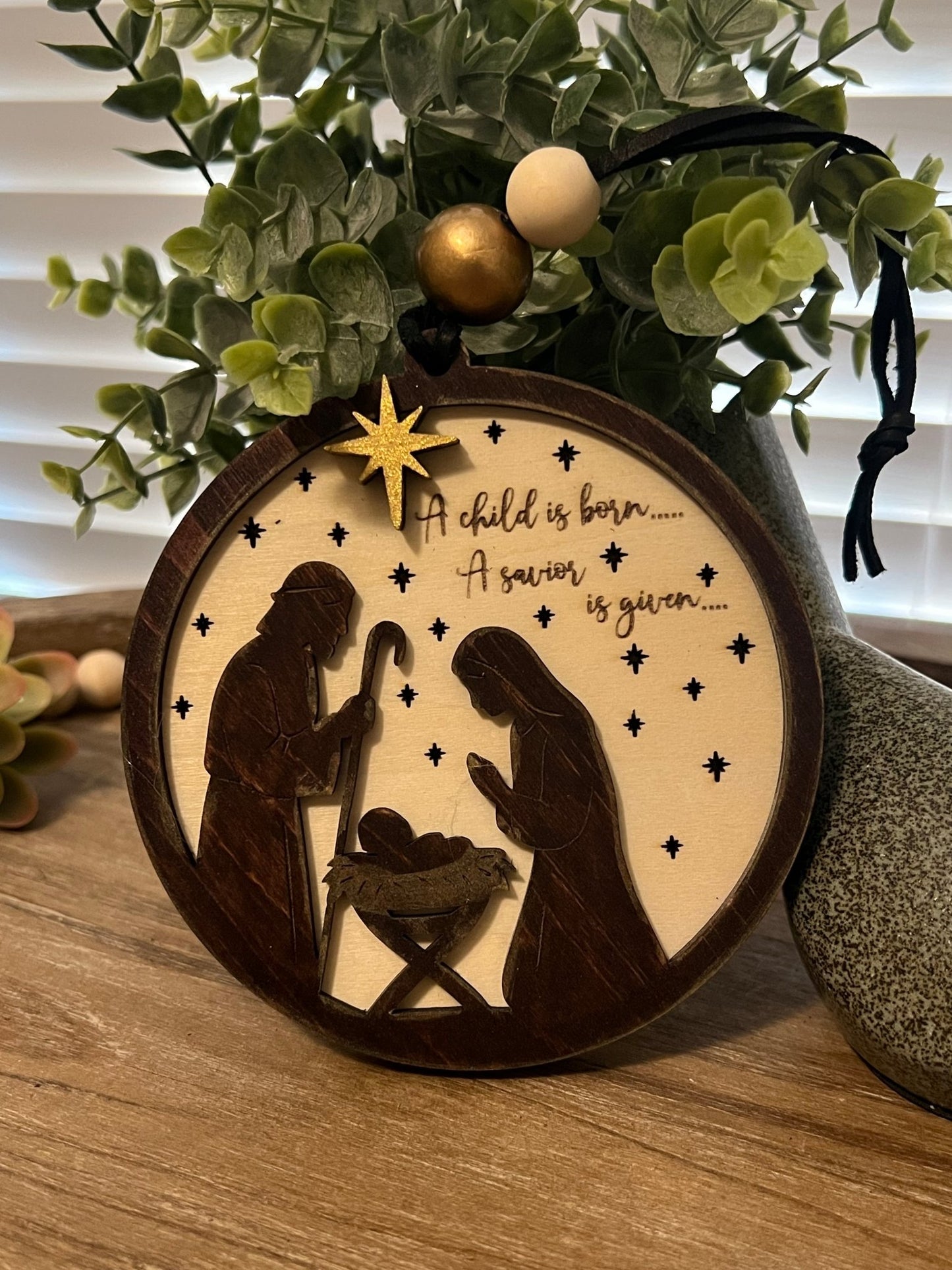 Lighted Christmas Nativity Ornament in natural wood with walnut stain lit in a darken room front view.