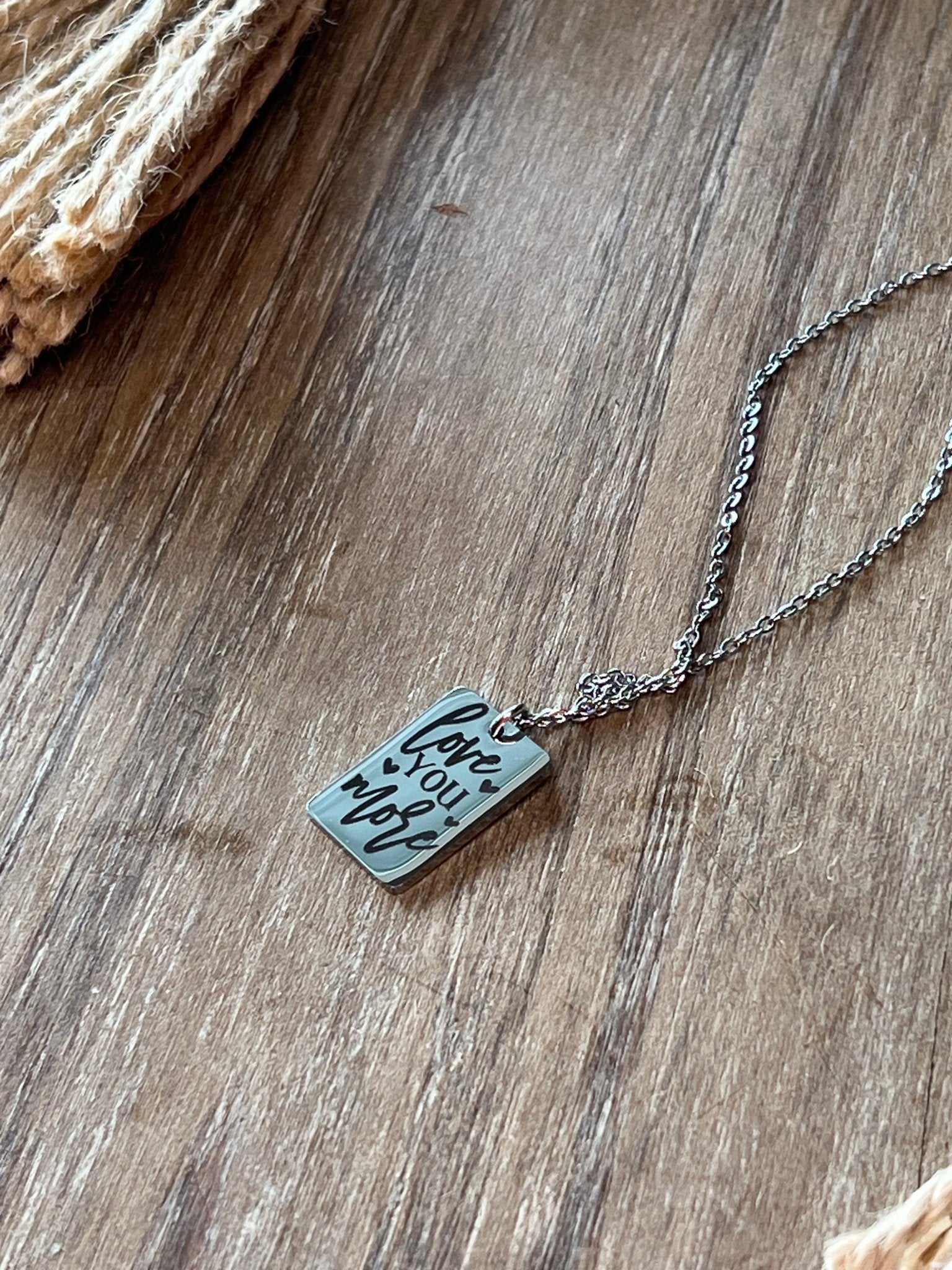 Engraved silver necklace made of stainless steel with a love message up close.