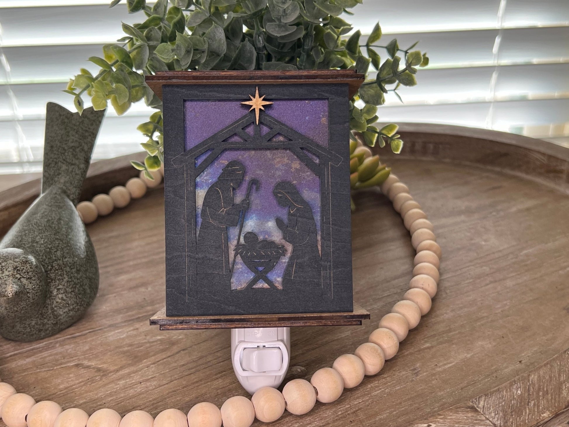 Rustic nativity nightlight lantern made of black wood and golden oak stained acrylic standing up with front view and unlit.