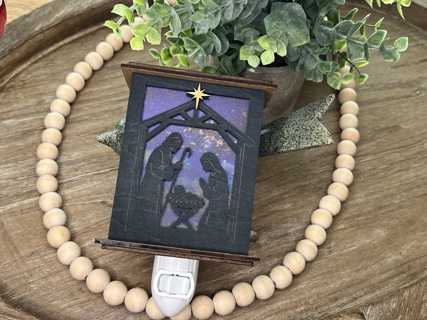 Rustic nativity nightlight lantern made of black wood and golden oak stained acrylic lynig down  with front view and unlit.