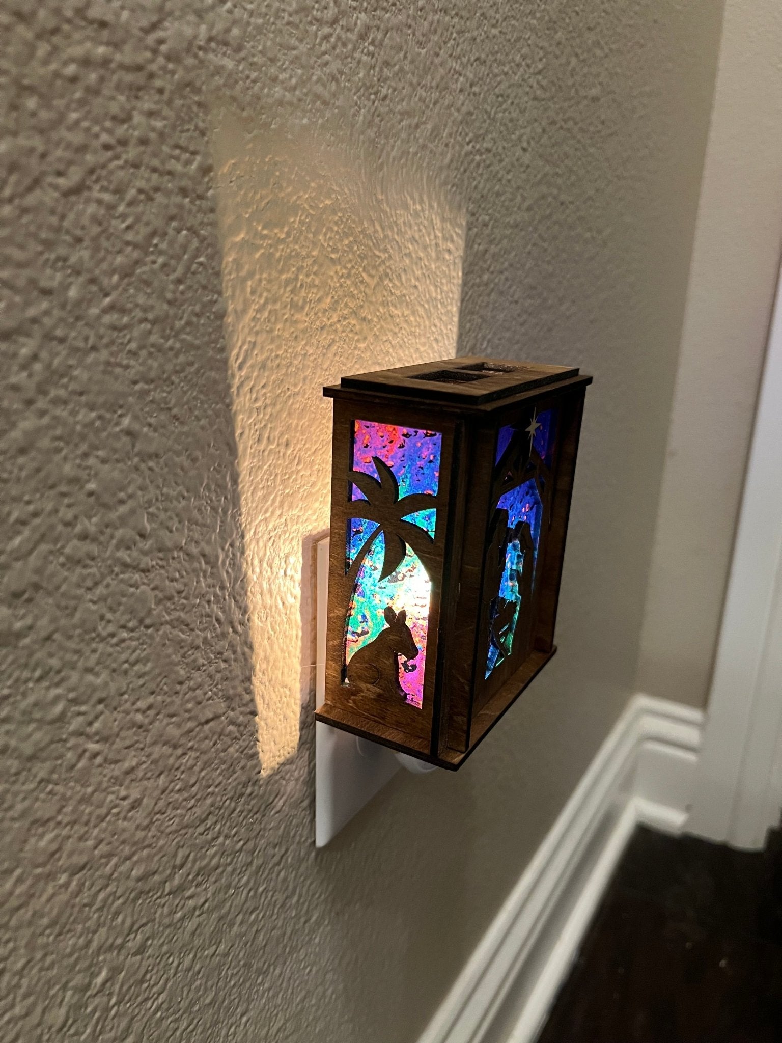 Golden oak stained wooden and acrylic nativity nightlight with rustic charm left view plugged in and lit.