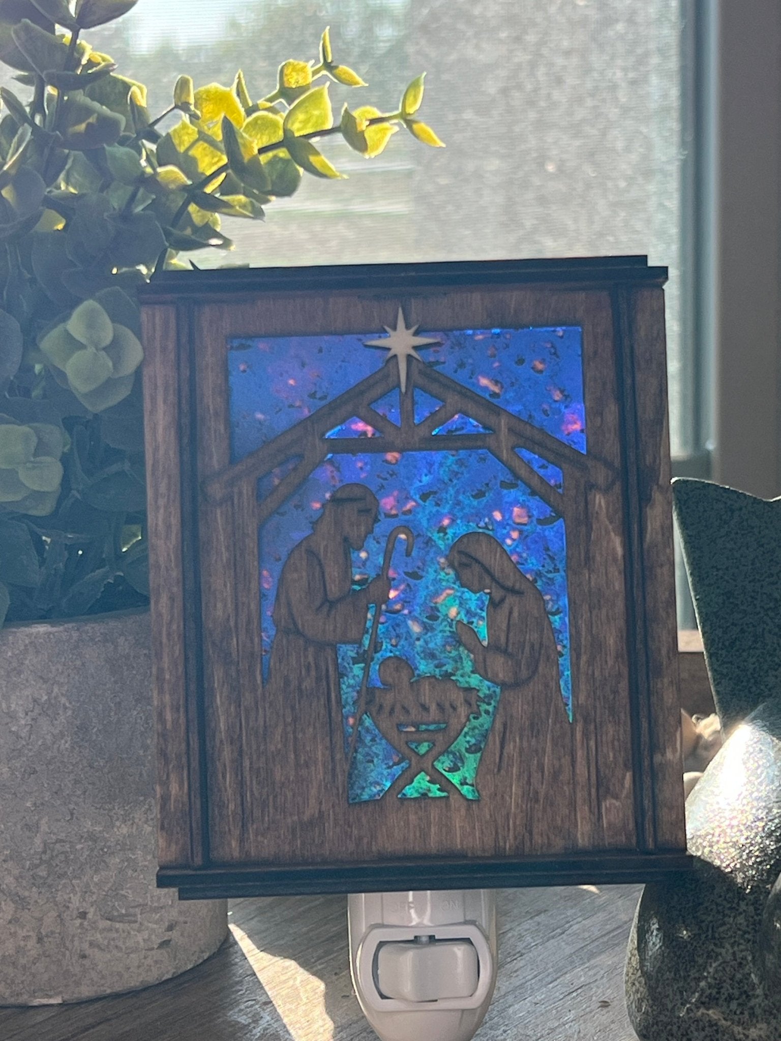 Golden oak stained wooden and acrylic nativity nightlight with rustic charm front view standing up wth sunilight shing through.