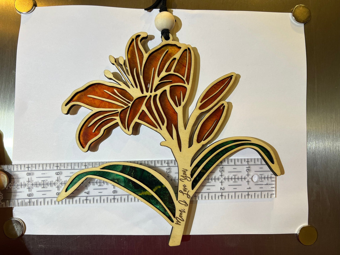 Orange Daylily stained glass effect suncatcher in wood and acrylic on white background with ruler.