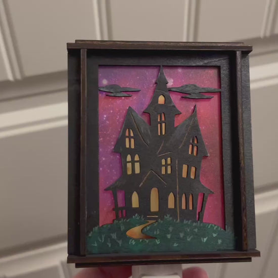 Video of a  haunted house hand painted stained glass effect nightlight, multicolor acrylic and black wood design.