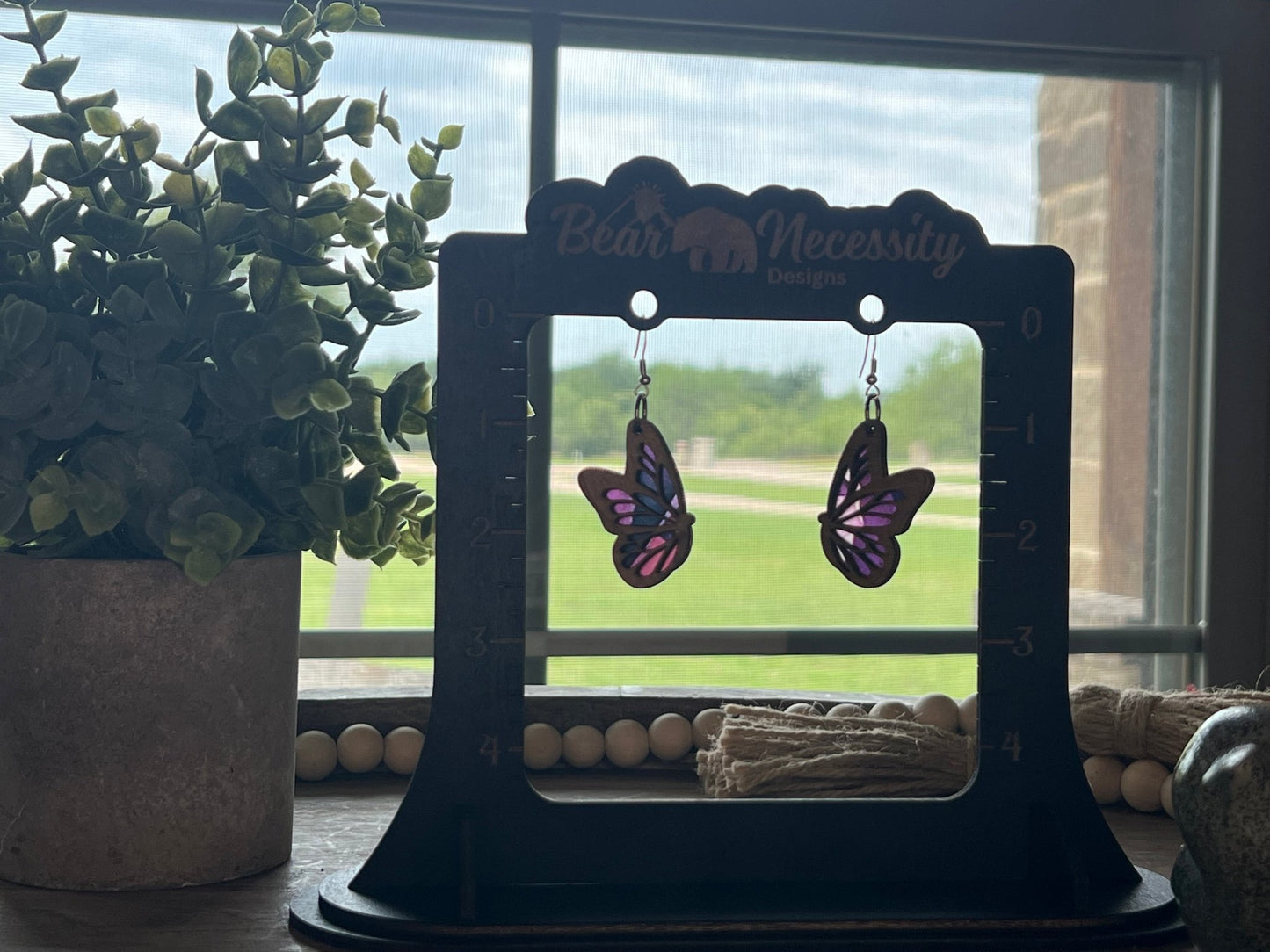 Purple Butterfly earrings made of wood and acrylic with a stained glass effect in sunlight.